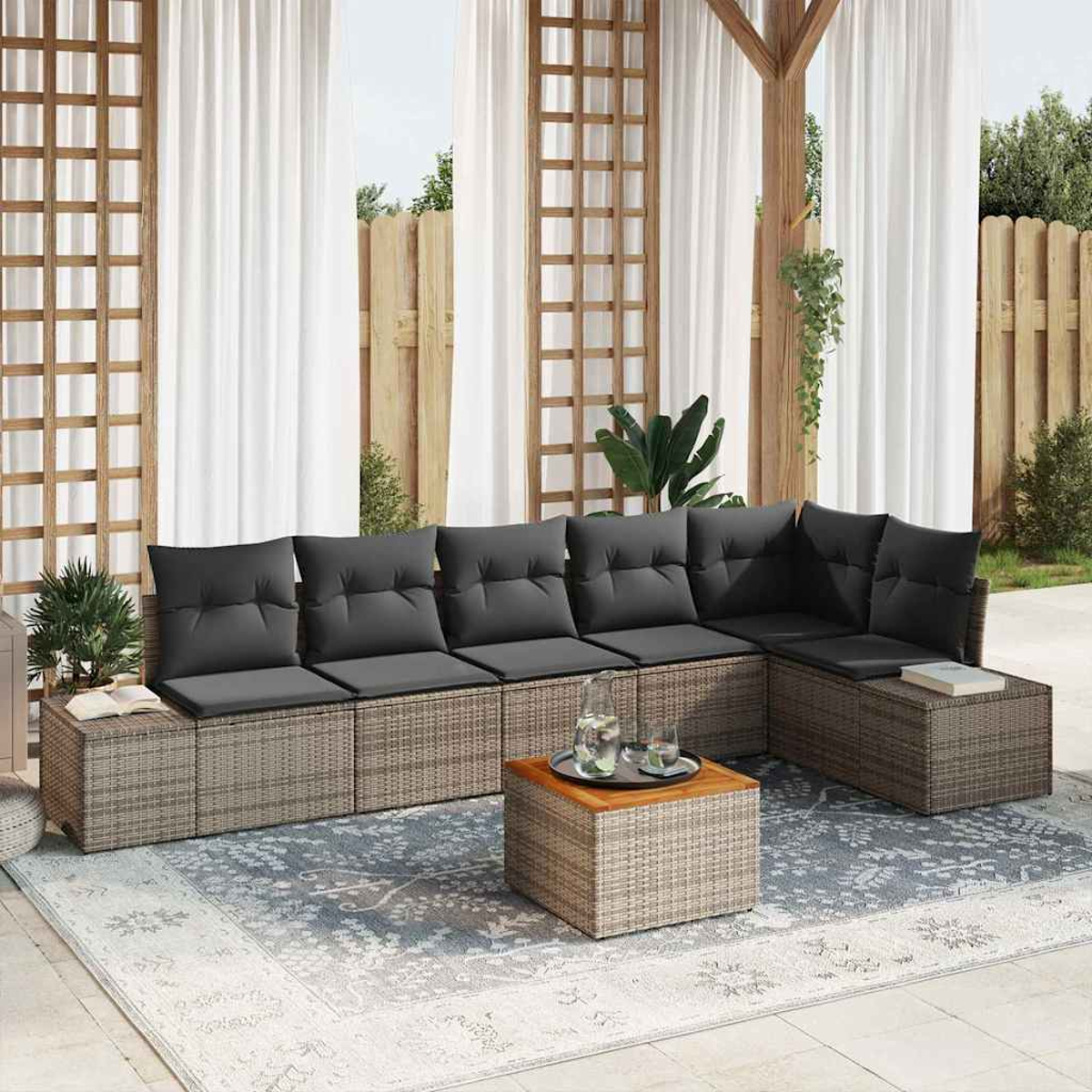 Outdoor-Ecksofa mit grauen Kissen. Ein kleiner Tisch mit Tablett und Gläsern steht auf einem Teppich. Weiße Vorhänge sind dahinter.