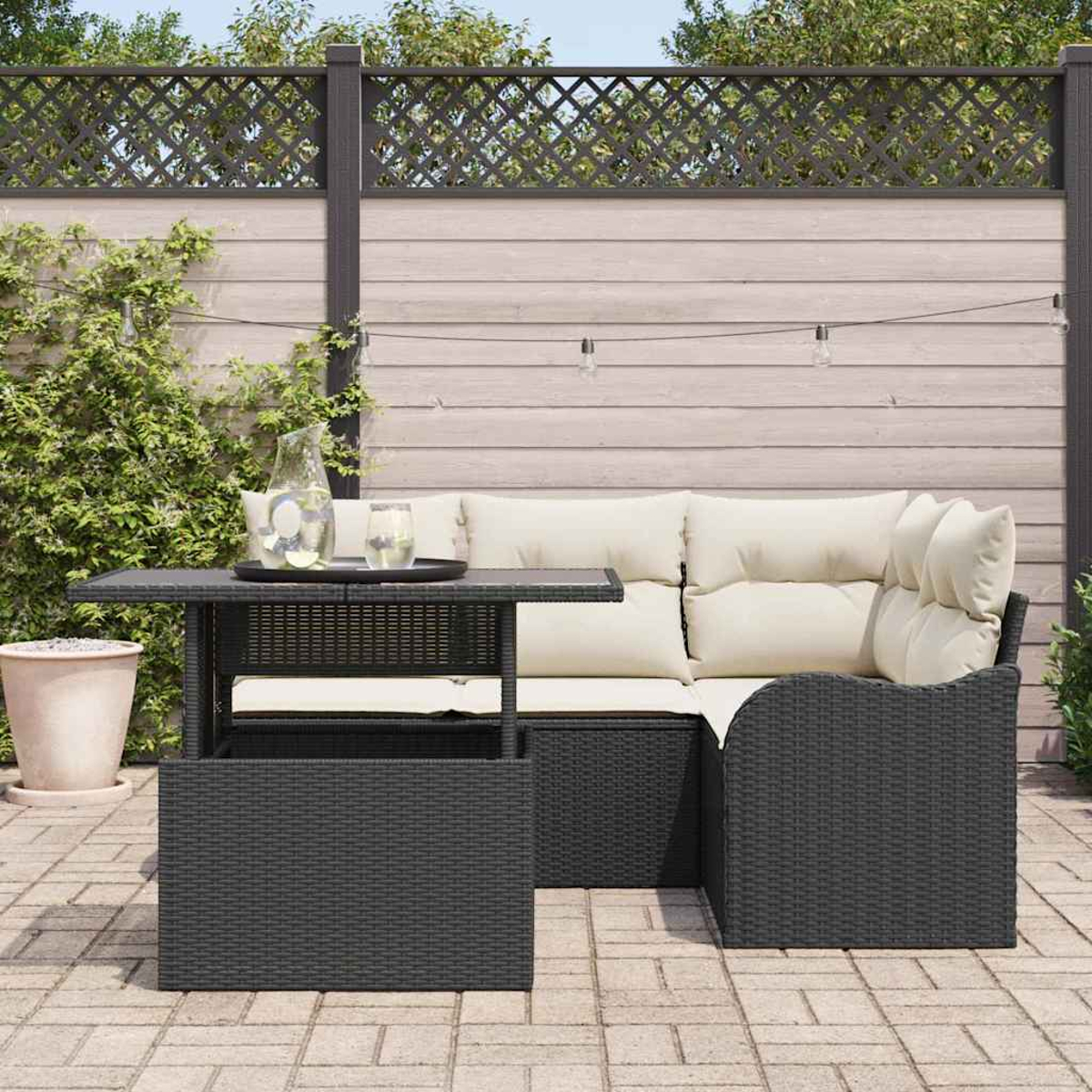 Garten-Terrassenset mit schwarzem Tisch, Korbsessel mit cremefarbenen Kissen und Holzzaun im Hintergrund.