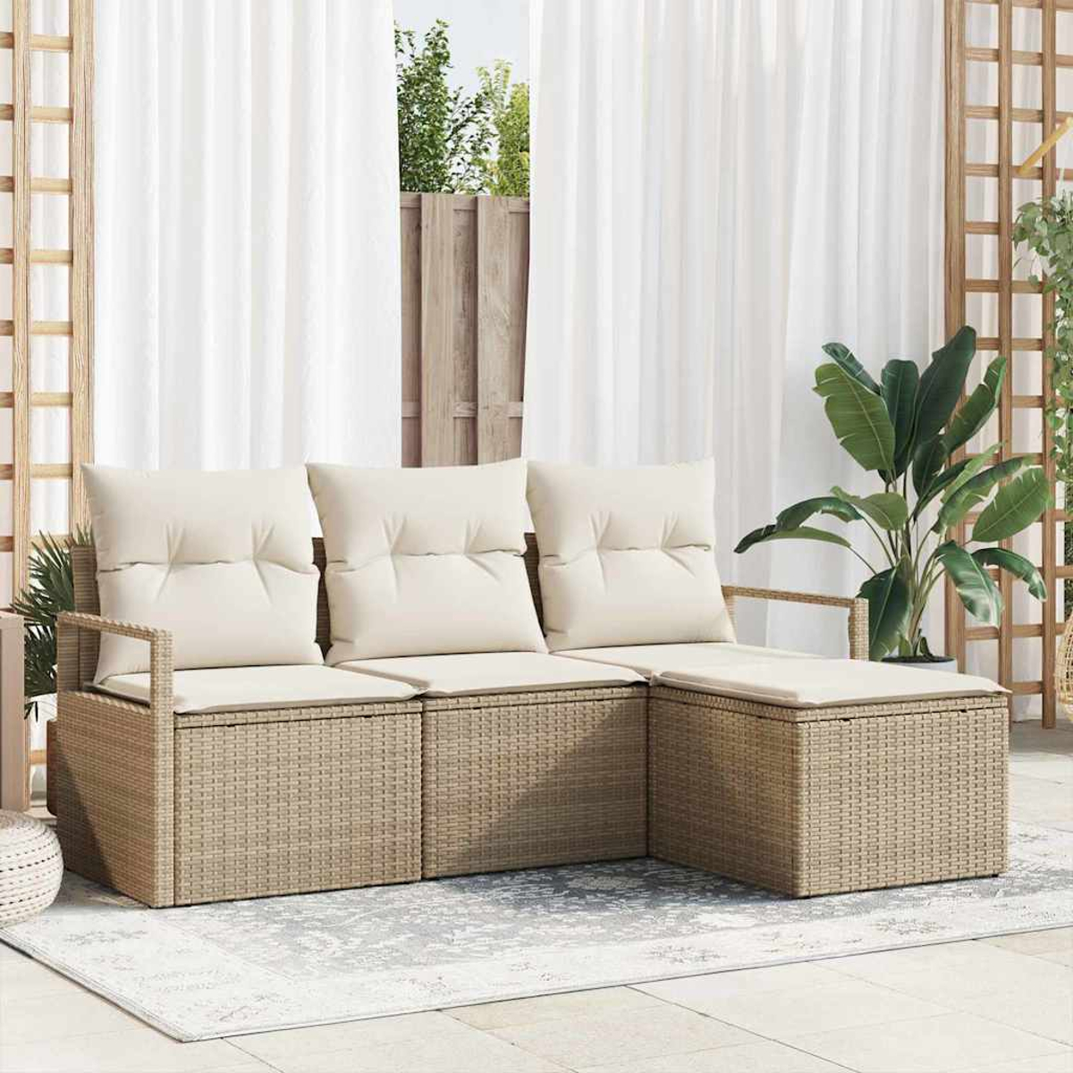 Ein Ecksofa aus Rattan mit cremefarbenen Kissen, eine große Pflanze und weiße Vorhänge im Hintergrund.
