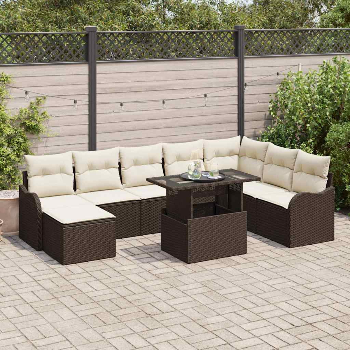 Ein Terrassenset mit braunen Korbmöbeln und beigefarbenen Kissen. Ein Tisch in der Mitte mit Gläsern darauf. Hinterhof mit Holzzaun.