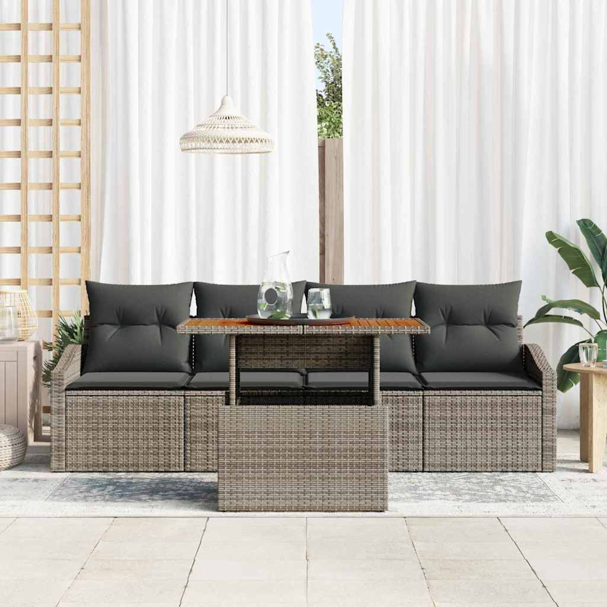 Szene im Freien mit einem Rattansofa, einem Couchtisch und weißen Vorhängen. Auf dem Tisch stehen ein Krug und Gläser. Eine Lampe hängt darüber.