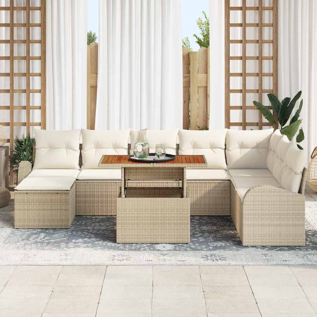 Garten-Sitzgruppe auf der Terrasse. Beiges Rattansofa mit weißen Kissen. Holztisch mit Getränken. Weiße Vorhänge und Holzgitter im Hintergrund.