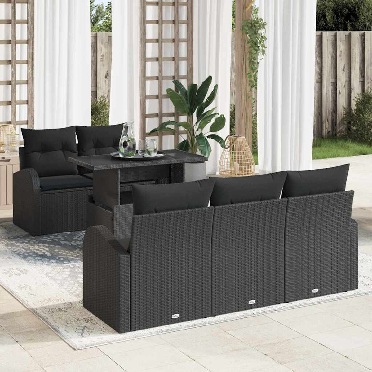 Garten-Terrassenset mit schwarzen Kissen und Tisch. Weiße Vorhänge und Holzgitter im Hintergrund. Eine Pflanze und eine dekorative Laterne.