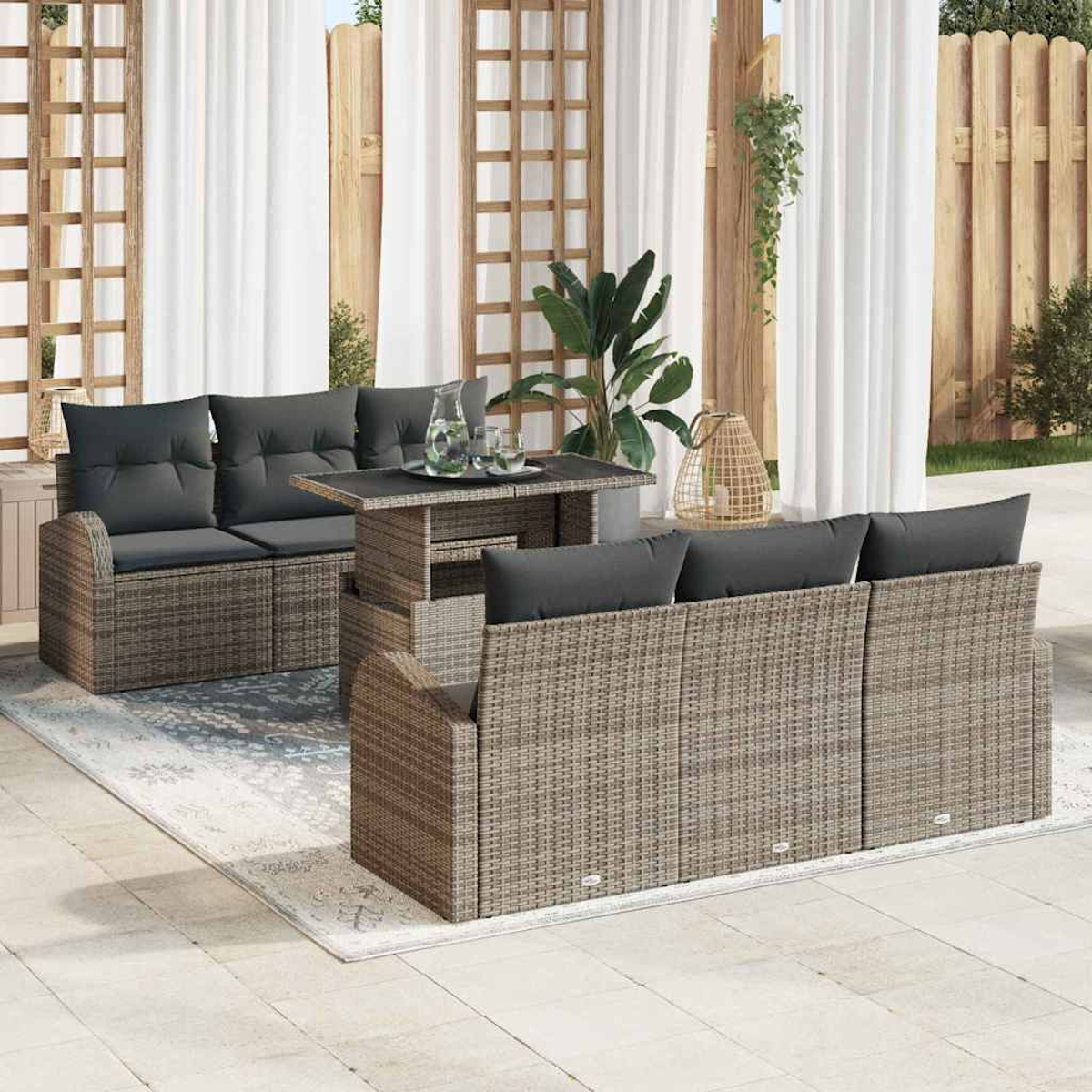 Gartenmöbel-Set aus Rattan mit grauen Kissen auf einer Terrasse. Enthält ein Sofa, eine Couch und einen Tisch vor weißen Vorhängen.