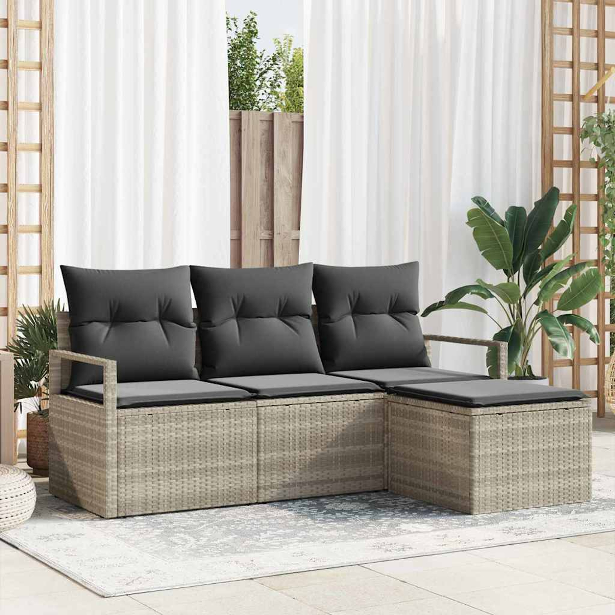 Rattan-Sofa im Freien mit grauen Kissen. Weiße Vorhänge im Hintergrund, eine Topfpflanze und ein Holzgitter.