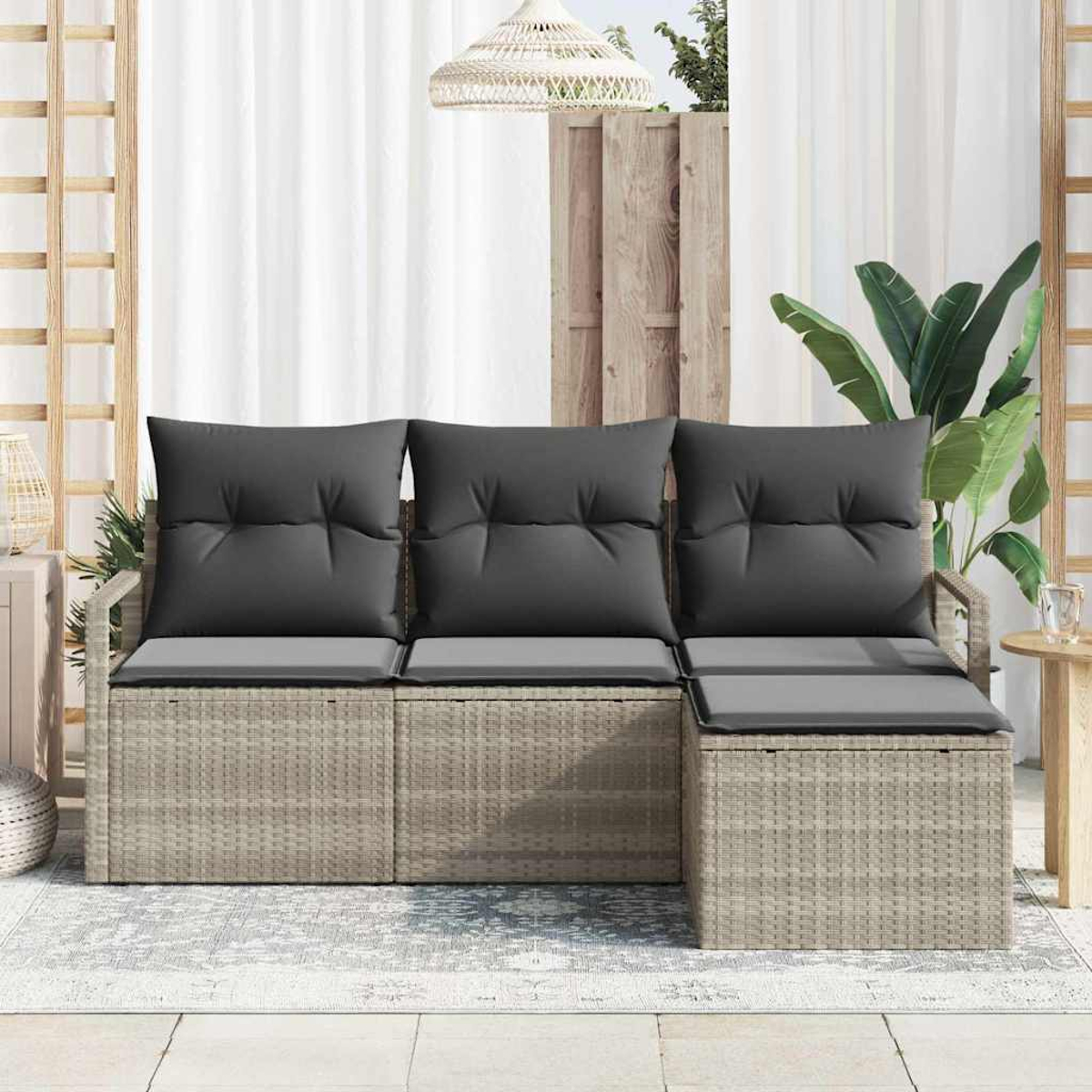 Korbsofa mit grauen Kissen. Dahinter ein weißer Vorhang, eine Holzwand und eine Pflanze. Eine Hängelampe ist ebenfalls vorhanden.