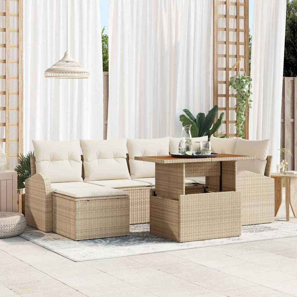 Terrassengarnitur mit beigen Korbmöbeln, weißen Kissen und einem Tisch mit Hubfunktion. Weiße Vorhänge und eine gewebte Lampe sind sichtbar.