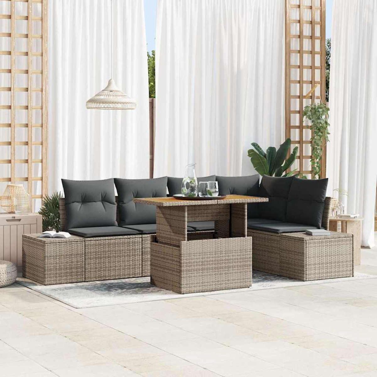 Geflochtenes Gartenmöbel-Set mit grauen Kissen, einem Couchtisch und weißen Vorhängen im Hintergrund.