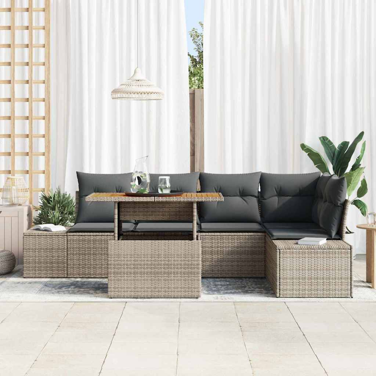 Outdoor-Sitzgruppe. Korbgeflechtrahmen mit grauen Kissen. Tisch mit Glaskrug und Glas. Weiße Vorhänge im Hintergrund.