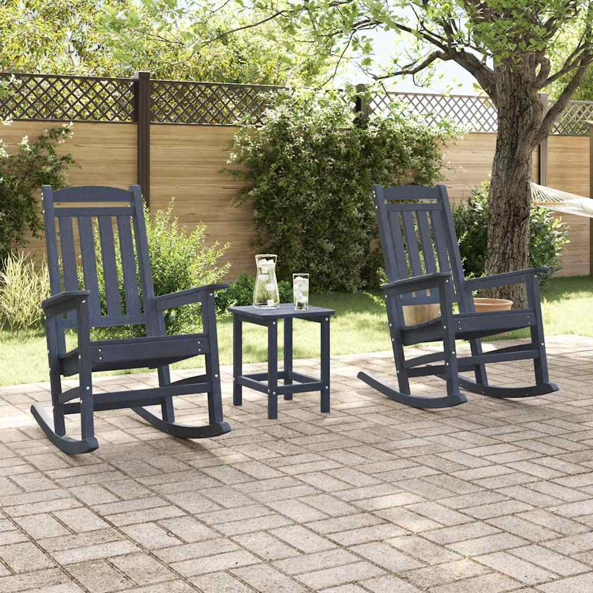 Zwei blaue Schaukelstühle, ein kleiner Tisch mit Getränken, stehen auf einer Backstein-Terrasse. Ein Zaun und Bäume bilden den Hintergrund.