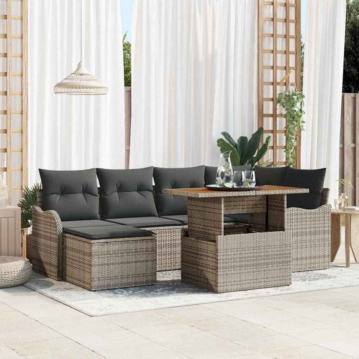 Garten-Terrassenset mit grauen Kissen, Korbmöbeln und einem Holztisch. Weiße Vorhänge und eine Hängelampe im Hintergrund.