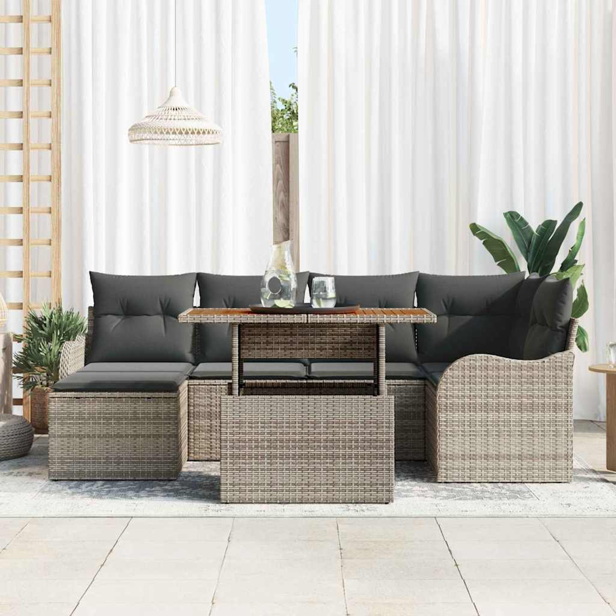 Garten-Korbsessel-Set mit grauen Kissen und einem Holztisch. Weiße Vorhänge und eine Hängelampe sind im Hintergrund.