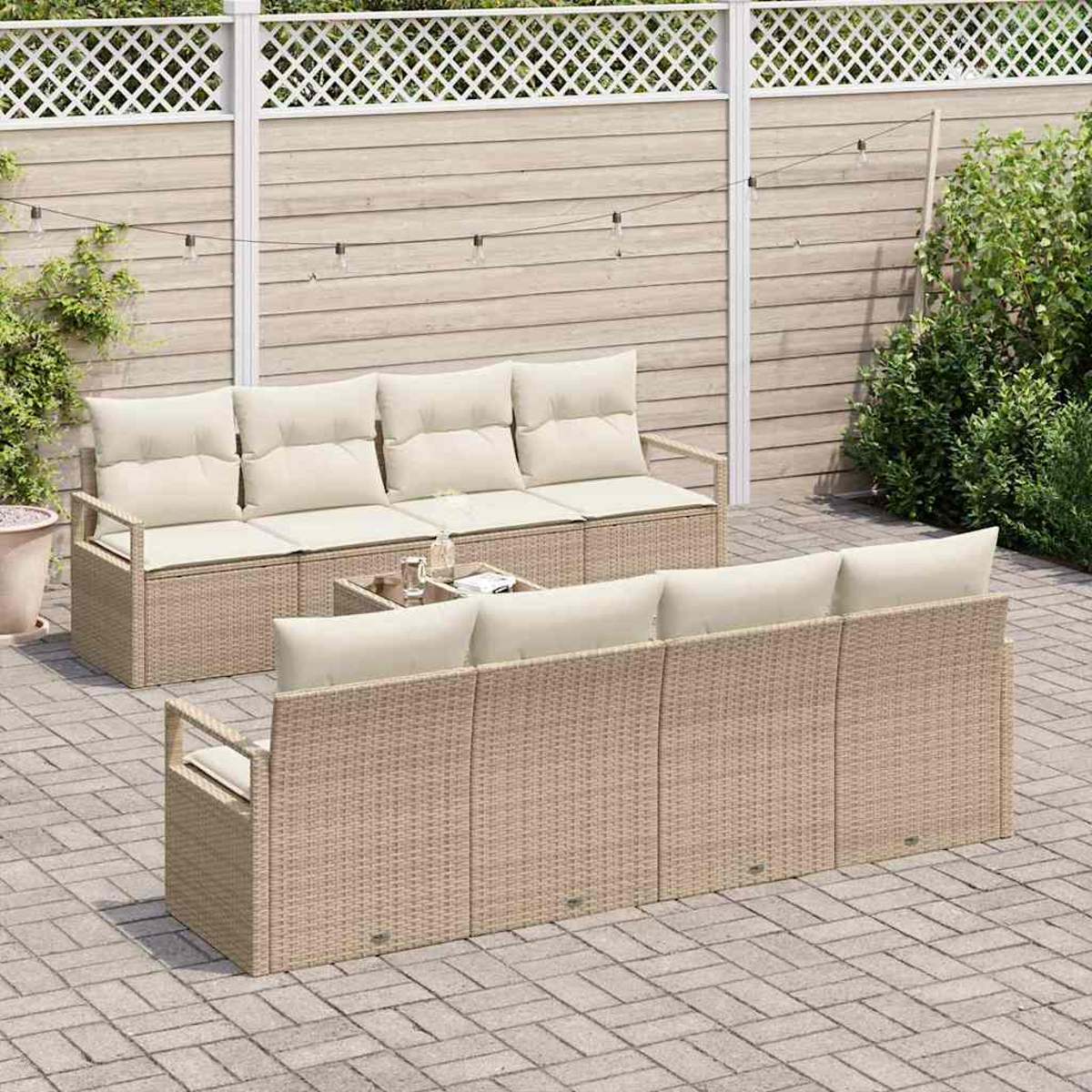 Szene im Freien mit Rattansofas, beigefarbenen Kissen und einem kleinen Tisch. Im Hintergrund ein Holzzaun, Pflanzen und Pflastersteine.