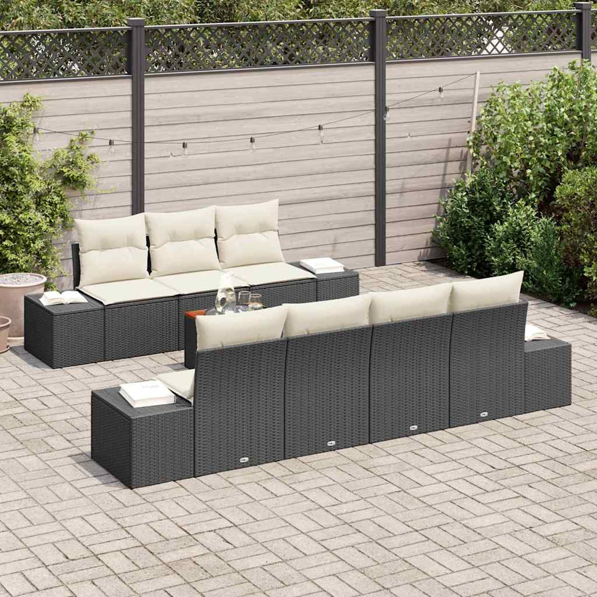 Gartenmöbel-Set mit dunkelgrauen Korbsesseln und hellen Kissen. In der Mitte steht ein Tisch mit Gläsern.