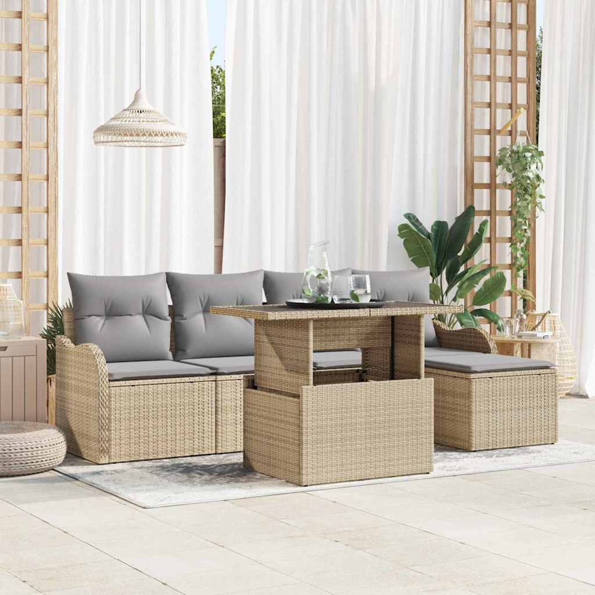 Terrassenset mit gewebtem Sofa, Tisch und Ottomane. Graue Kissen und weiße Vorhänge im Hintergrund. Pflanzen und eine Hängelampe.
