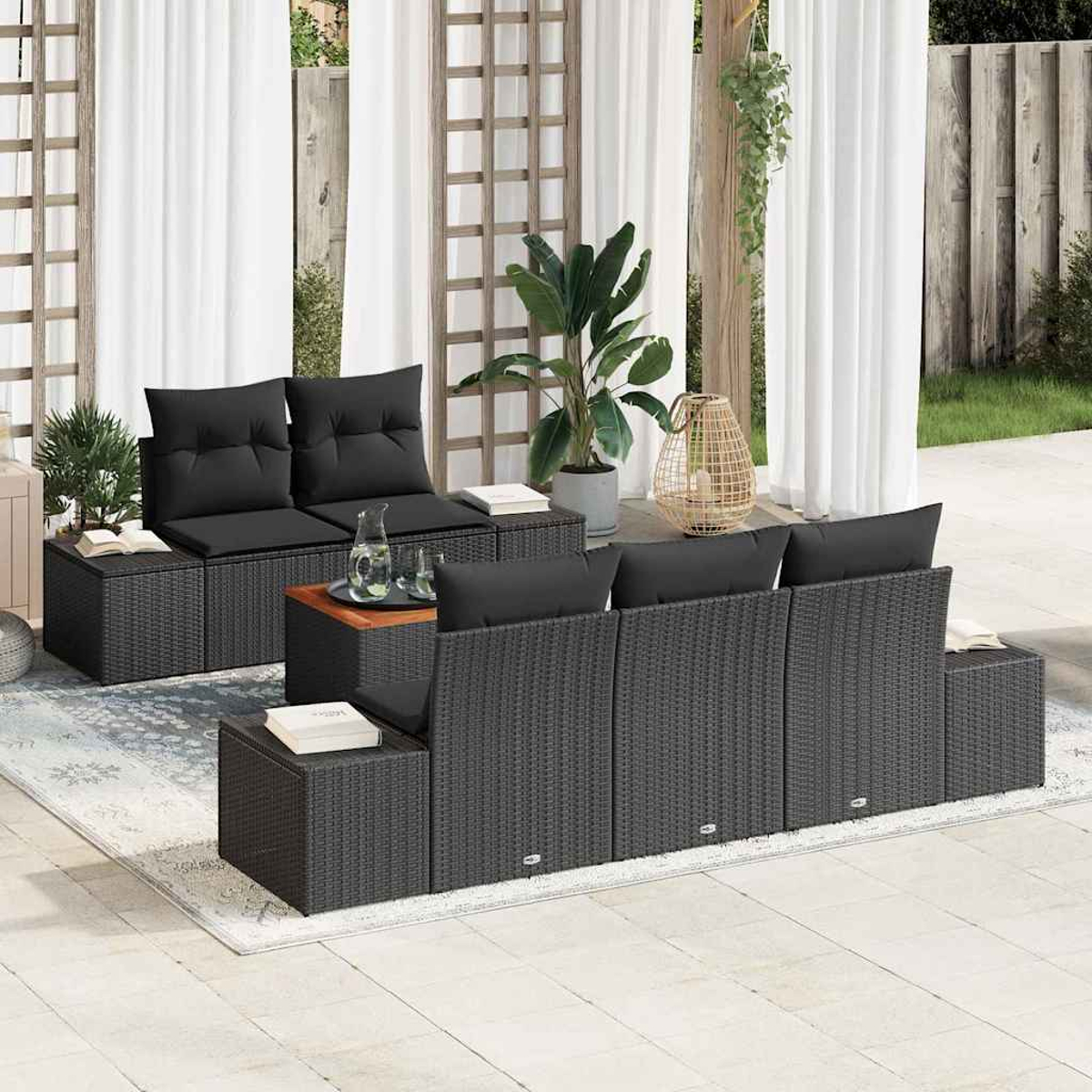 Terrassenset mit schwarzen Kissen und Korbmöbeln. Enthält Sofa, Stühle und Tische. Pflanzen und Vorhänge im Hintergrund.