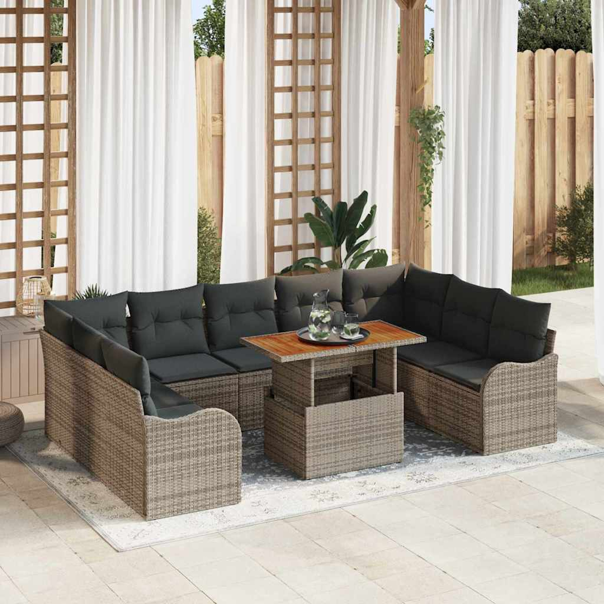 Rattan-Outdoor-Ecksofa mit dunklen Kissen und einem Tisch mit Getränken, auf einem Teppich. Weiße Vorhänge im Hintergrund.