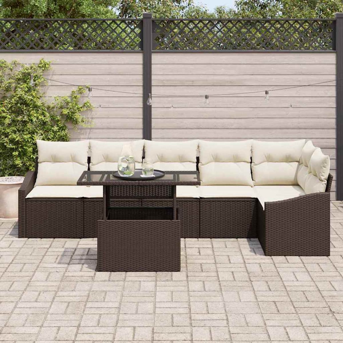 Outdoor-Ecksofa mit cremefarbenen Kissen. Davor steht ein kleiner Tisch mit Tablett und Gläsern. Im Hintergrund eine Backstein-Terrasse und ein Zaun.
