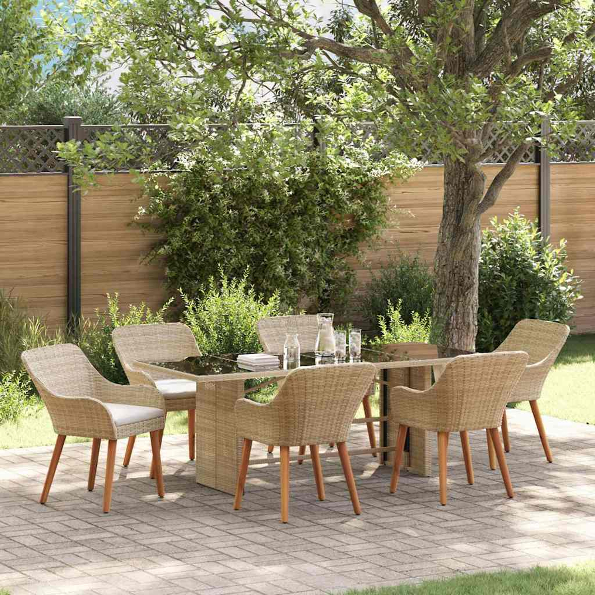 Juego de comedor al aire libre con seis sillas de mimbre alrededor de una mesa con tapa de cristal. Jardín con árboles y valla de madera.
