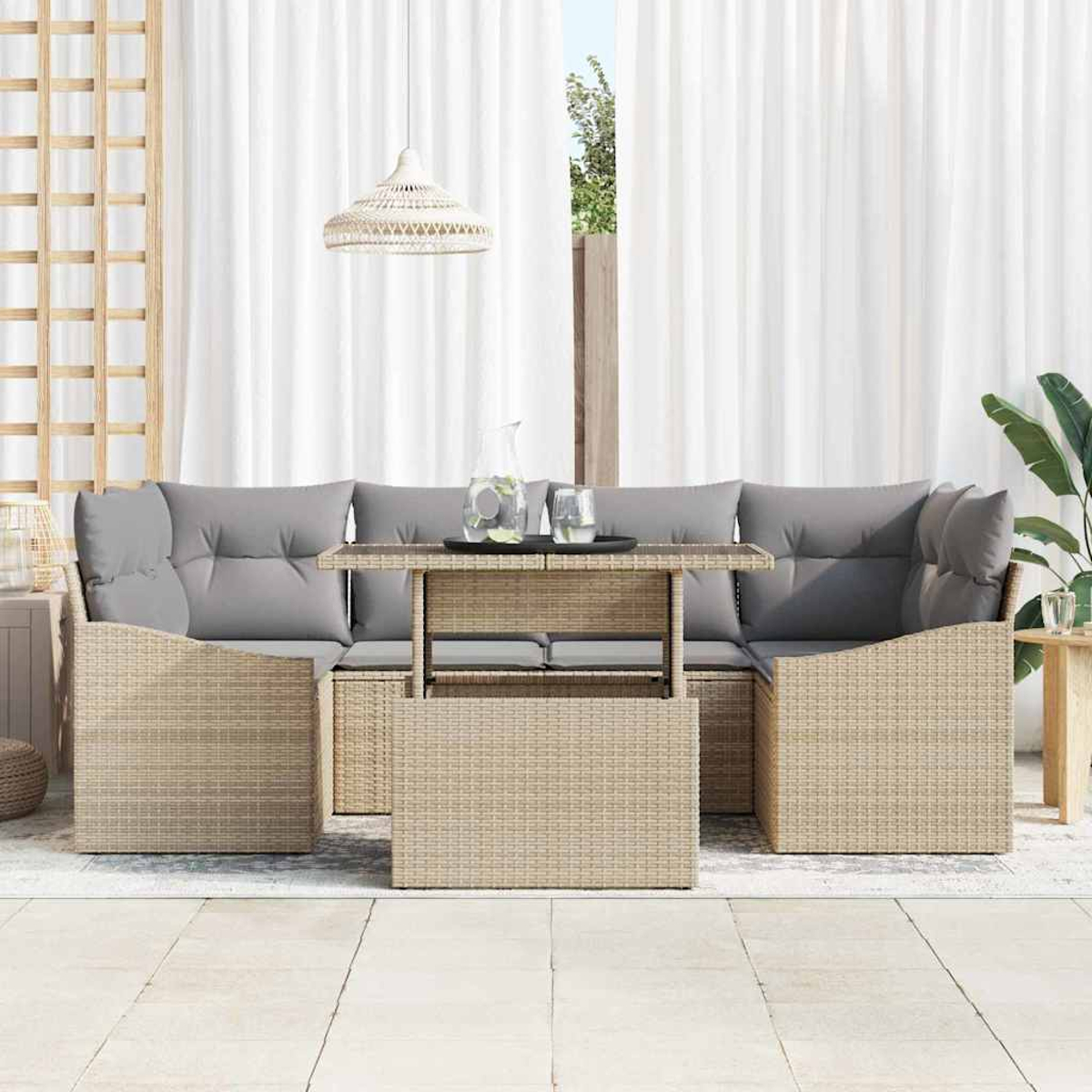 Outdoor-Sitzgruppe mit Tisch. Graue Kissen, beiges Korbgeflecht, weiße Vorhänge und eine Hängelampe. Klare Gläser und eine Wasserkaraffe.
