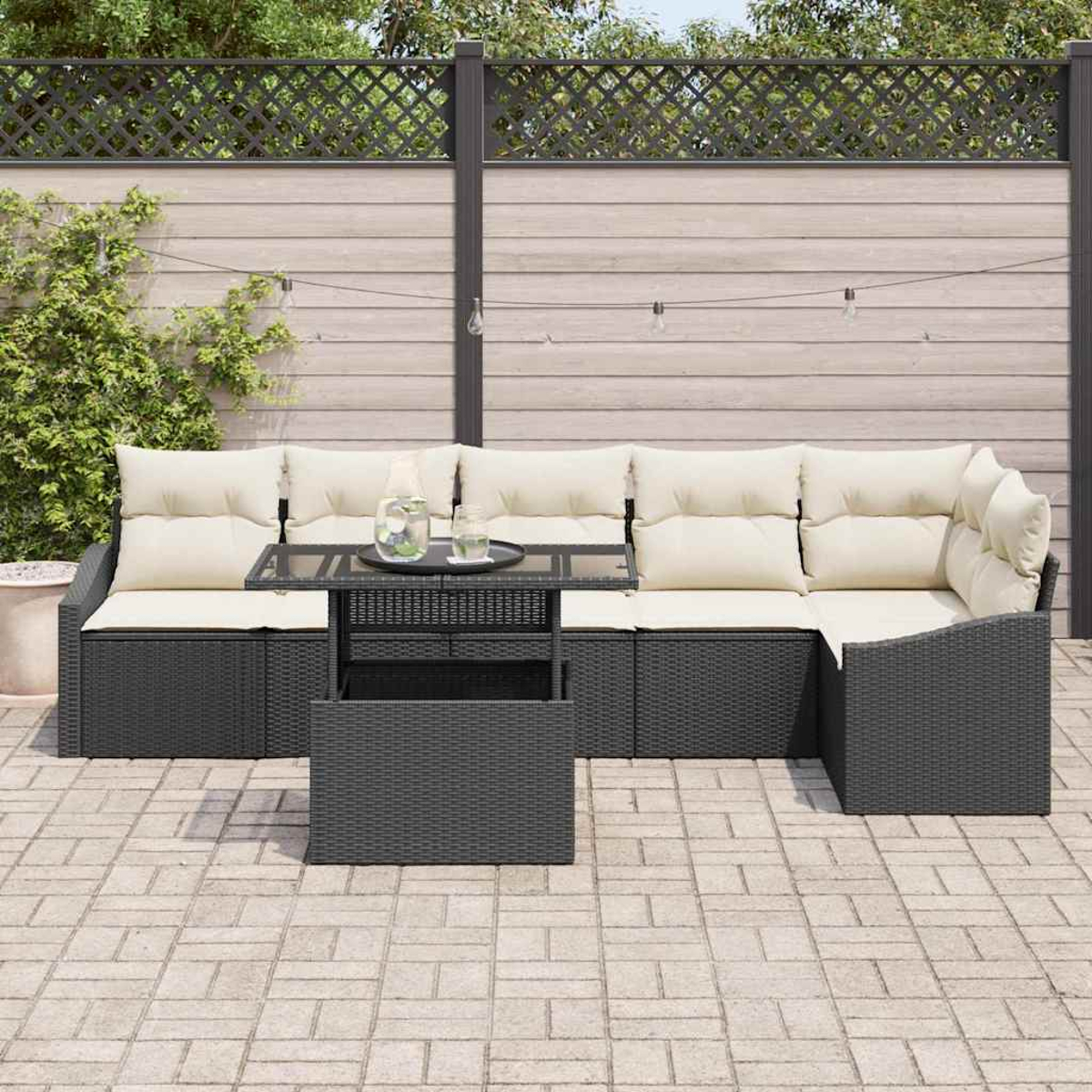 Sofá seccional al aire libre con cojines crema, mimbre negro y una mesa pequeña. Valla de madera en el fondo.