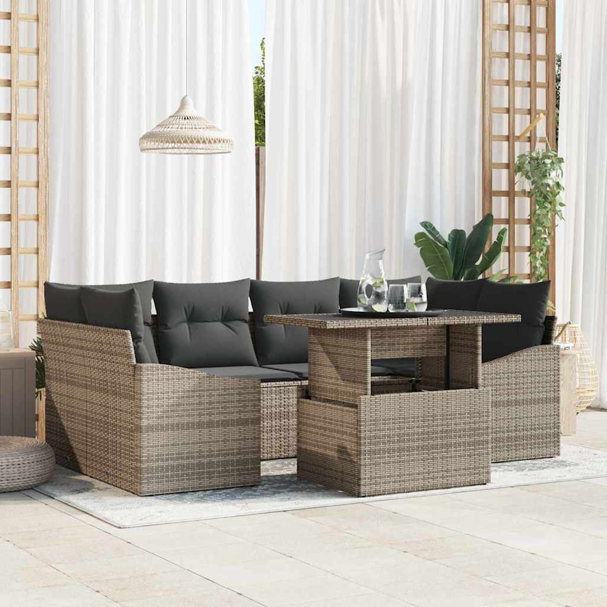 Gartenmöbel-Set aus Weide mit grauen Kissen, einem Tisch mit Gläsern und einem Krug sowie weißen Vorhängen im Hintergrund.