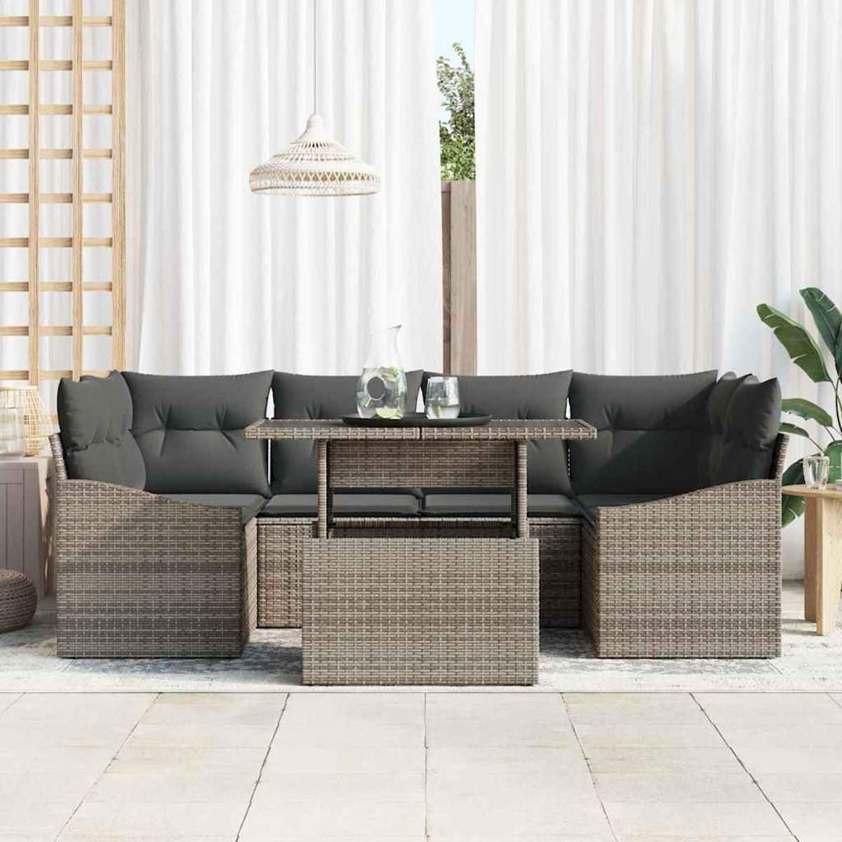 Gartenmöbel-Set aus Korbgeflecht mit grauen Kissen und einem Tisch mit Glasplatte. Weiße Vorhänge und eine Hängeleuchte im Hintergrund.