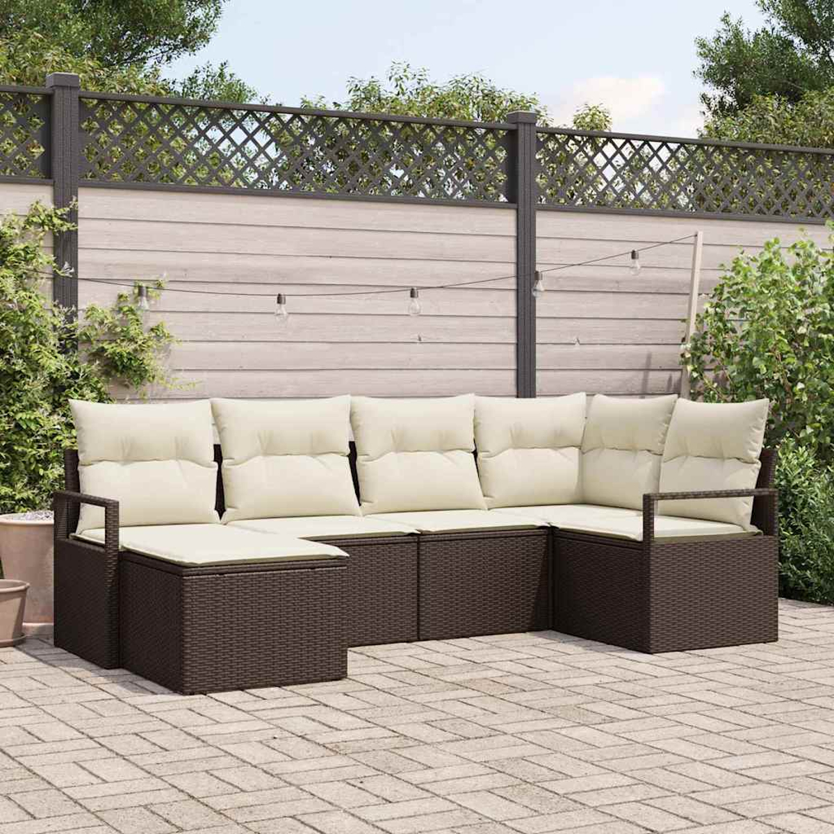 Outdoor-Ecksofa mit cremefarbenen Kissen auf einer Backstein-Terrasse. Dahinter ein Holzzaun mit Zierleiste und Lichterkette.