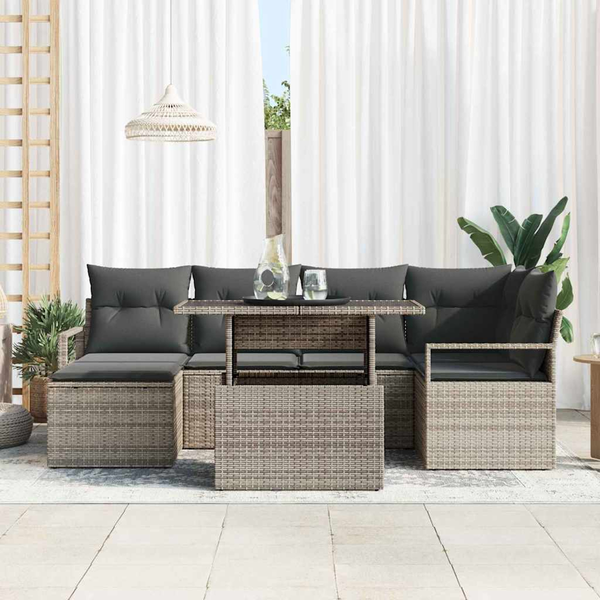 Gartenmöbel-Set mit grauen Kissen, einem Tisch mit Glasplatte und weißen Vorhängen im Hintergrund.