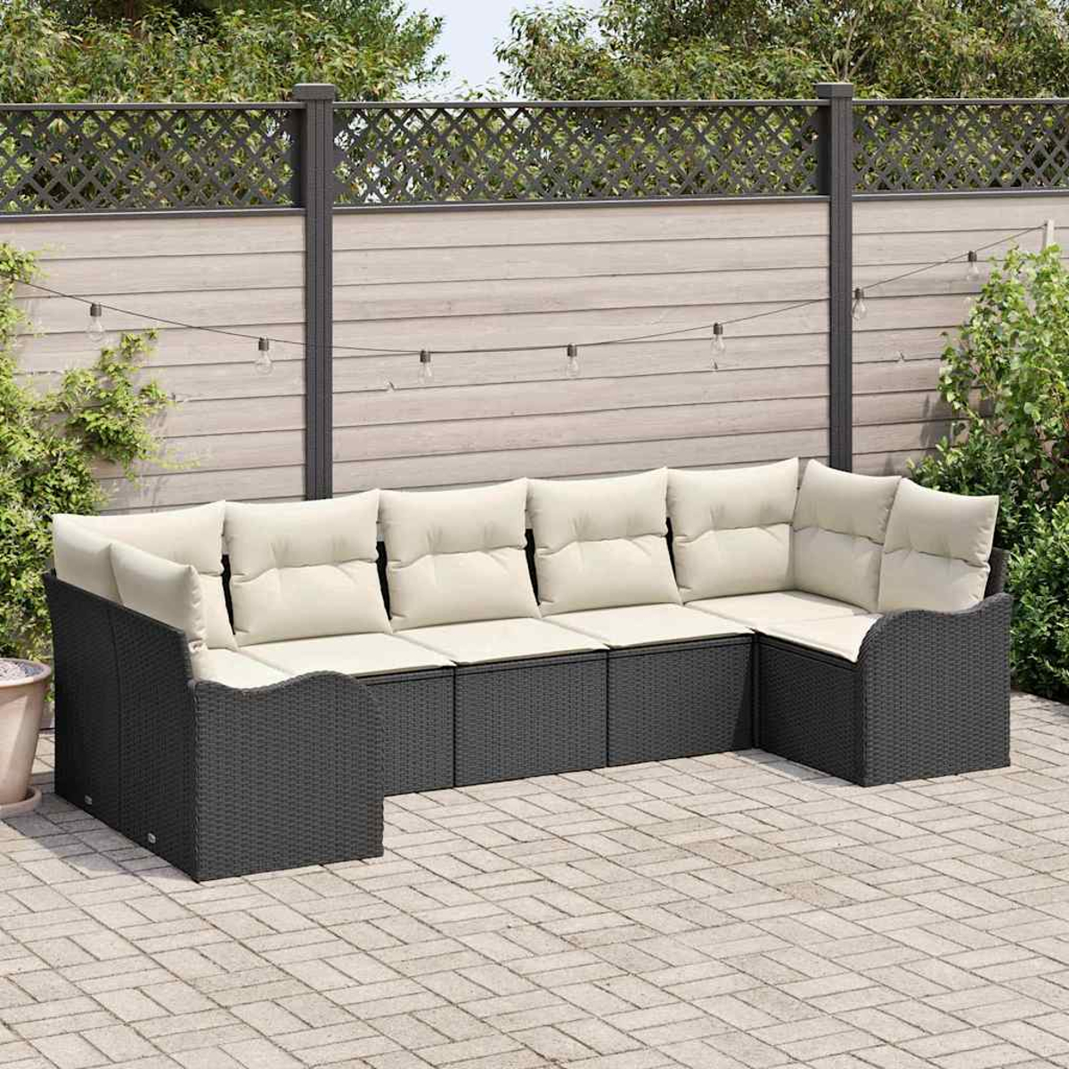 Ein dunkelgraues Korbsessel-Sofa mit cremefarbenen Kissen steht auf einer Ziegelpatio. Im Hintergrund befinden sich ein Holzzaun und Lichterketten.