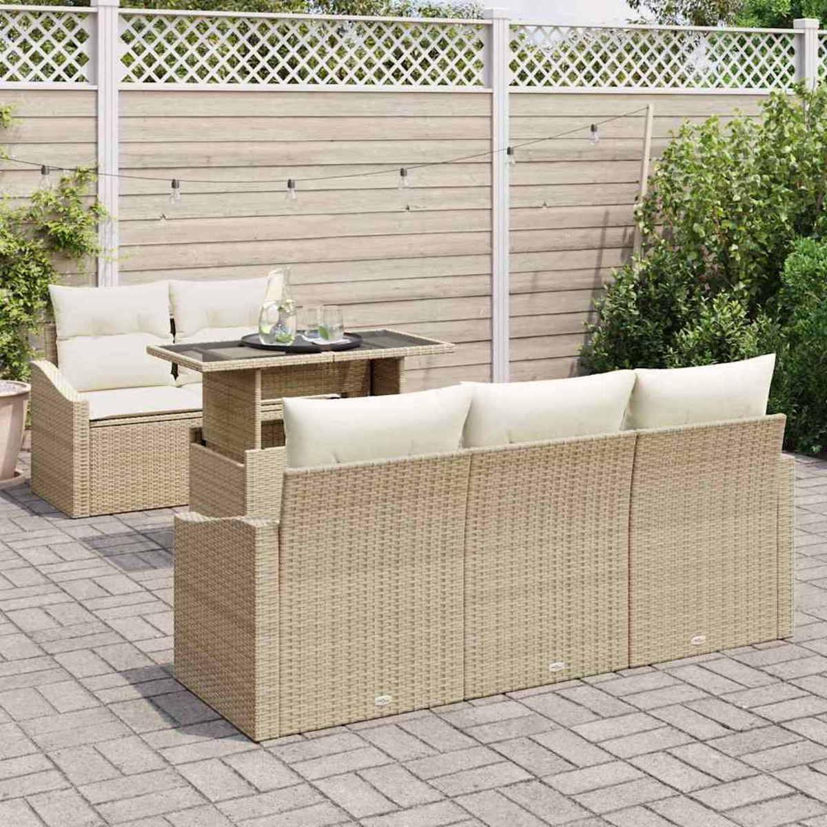 Gartenmöbel-Set: ein Korbsessel und -sofa mit cremefarbenen Kissen und einem Tisch auf einer gepflasterten Terrasse, mit Zaun im Hintergrund.