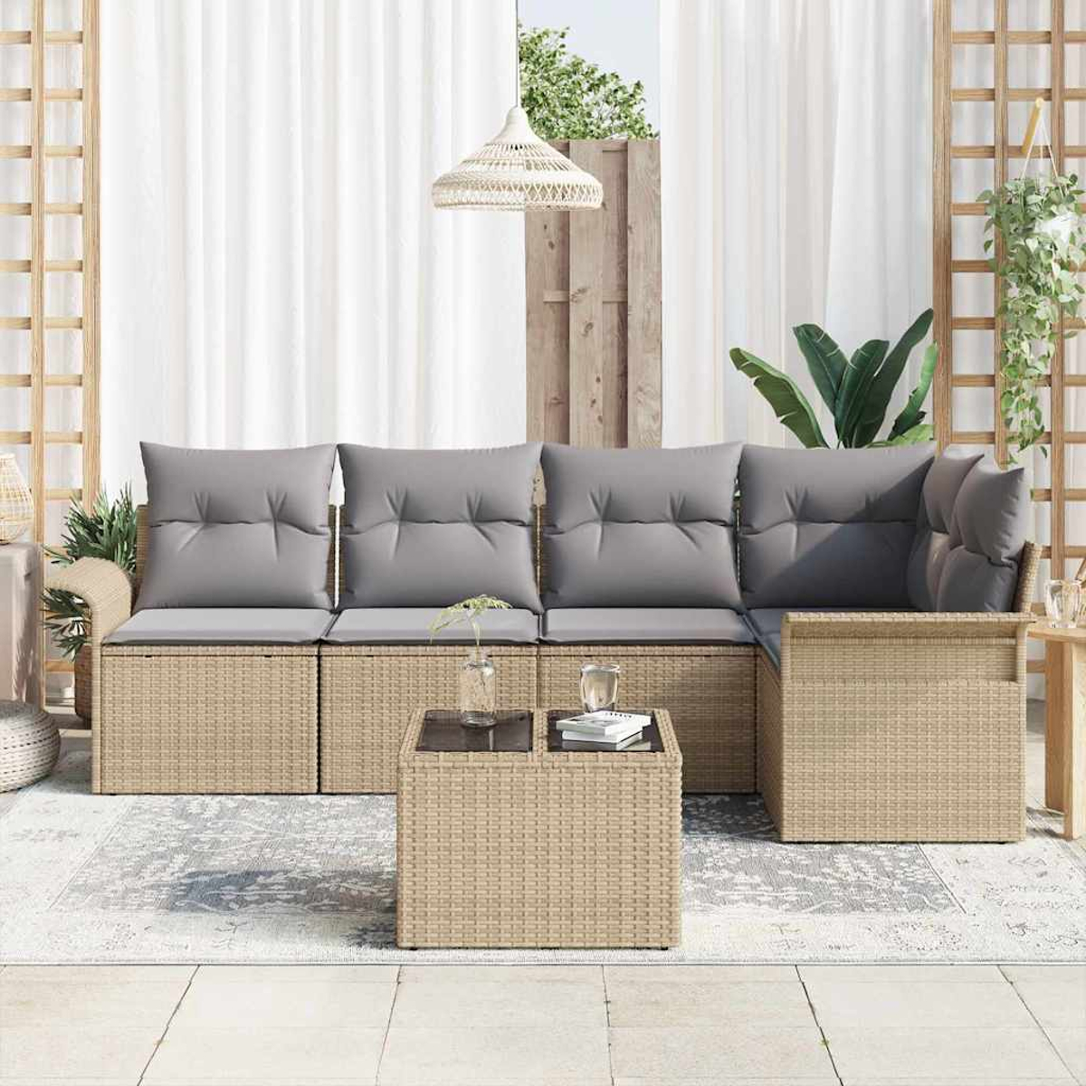 Outdoor-Sitzbereich mit Korbmöbeln, grauen Kissen und einem Couchtisch mit Glasplatte, mit weißen Vorhängen und Pflanzen.