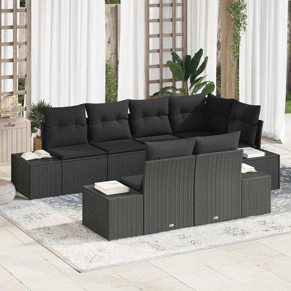 Outdoor-Ecksofa mit schwarzen Kissen. Dunkelgraue Rattanmöbel stehen auf einem hellen Teppich. Weiße Vorhänge im Hintergrund.