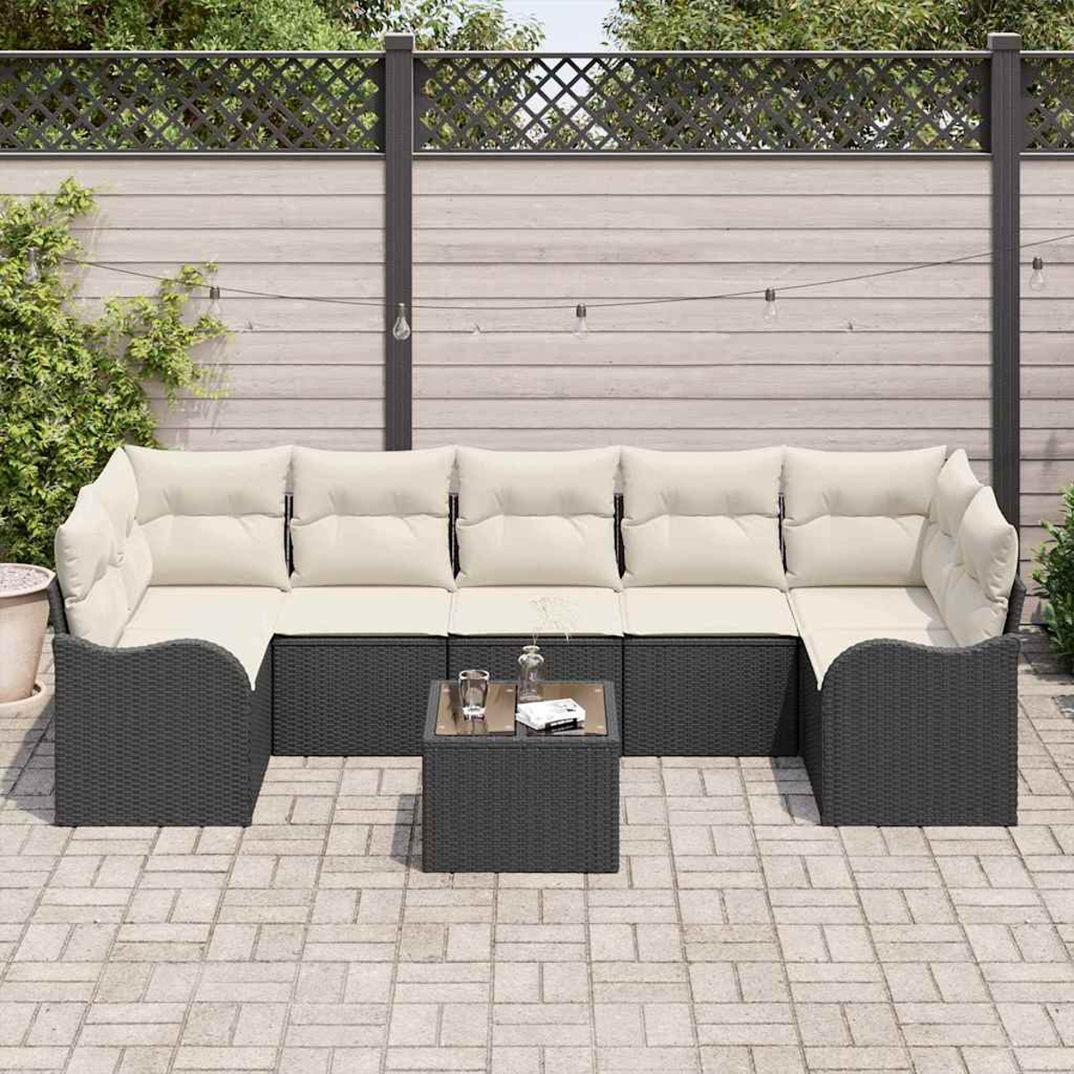 Outdoor-Ecksofa mit beigen Kissen und dunkelgrauem Rahmen, quadratischer Couchtisch, auf einer Terrasse. Holzzaun im Hintergrund.