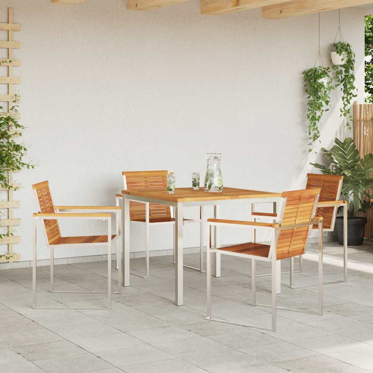 Essgruppe im Freien mit Holztisch und Stühlen. Getränke auf dem Tisch. Pflanzen im Hintergrund. Weiße Wand und Fliesenboden.