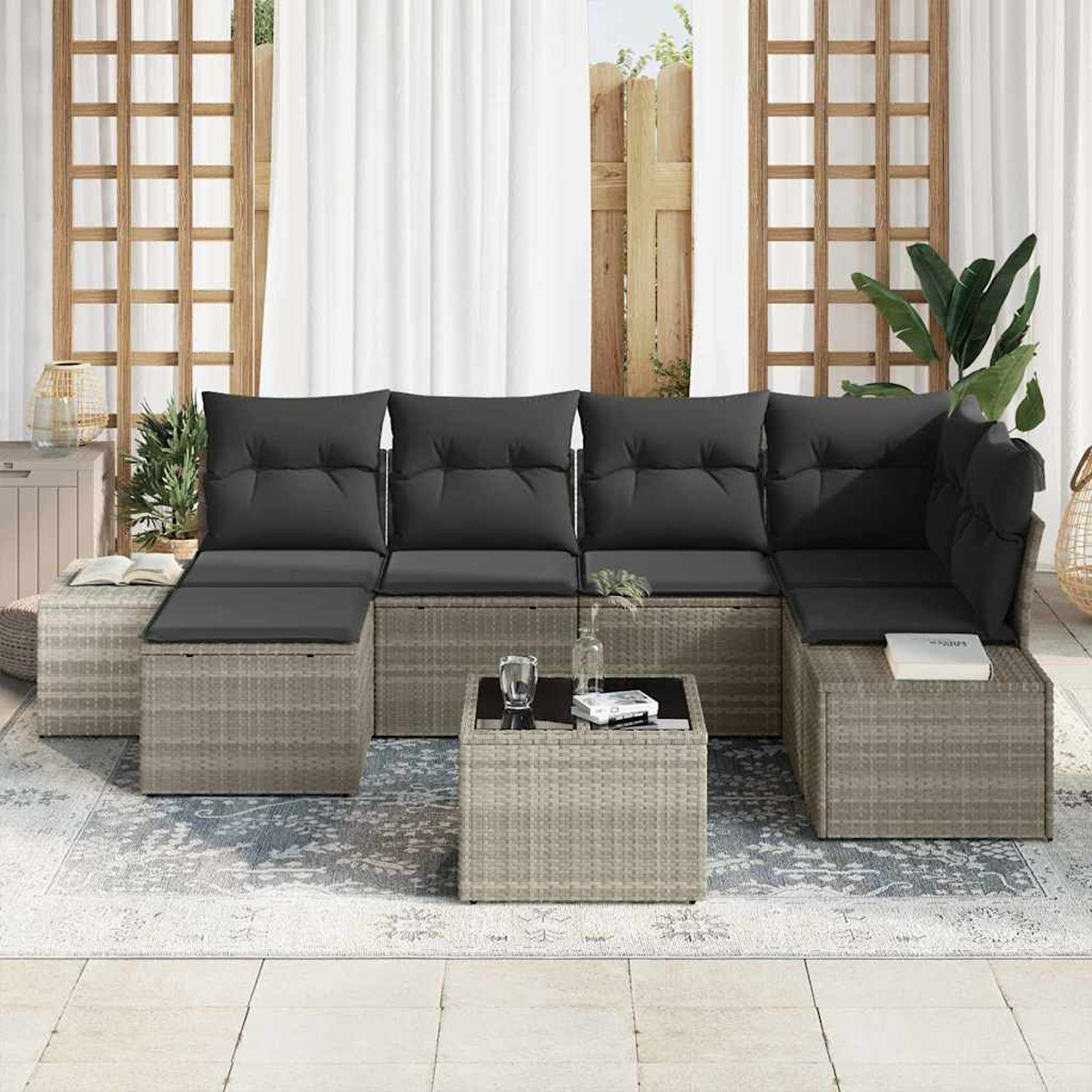 Outdoor-Ecksofa mit schwarzen Kissen und einem Couchtisch auf einem gemusterten Teppich. Der Hintergrund umfasst Vorhänge und einen Holzzaun.
