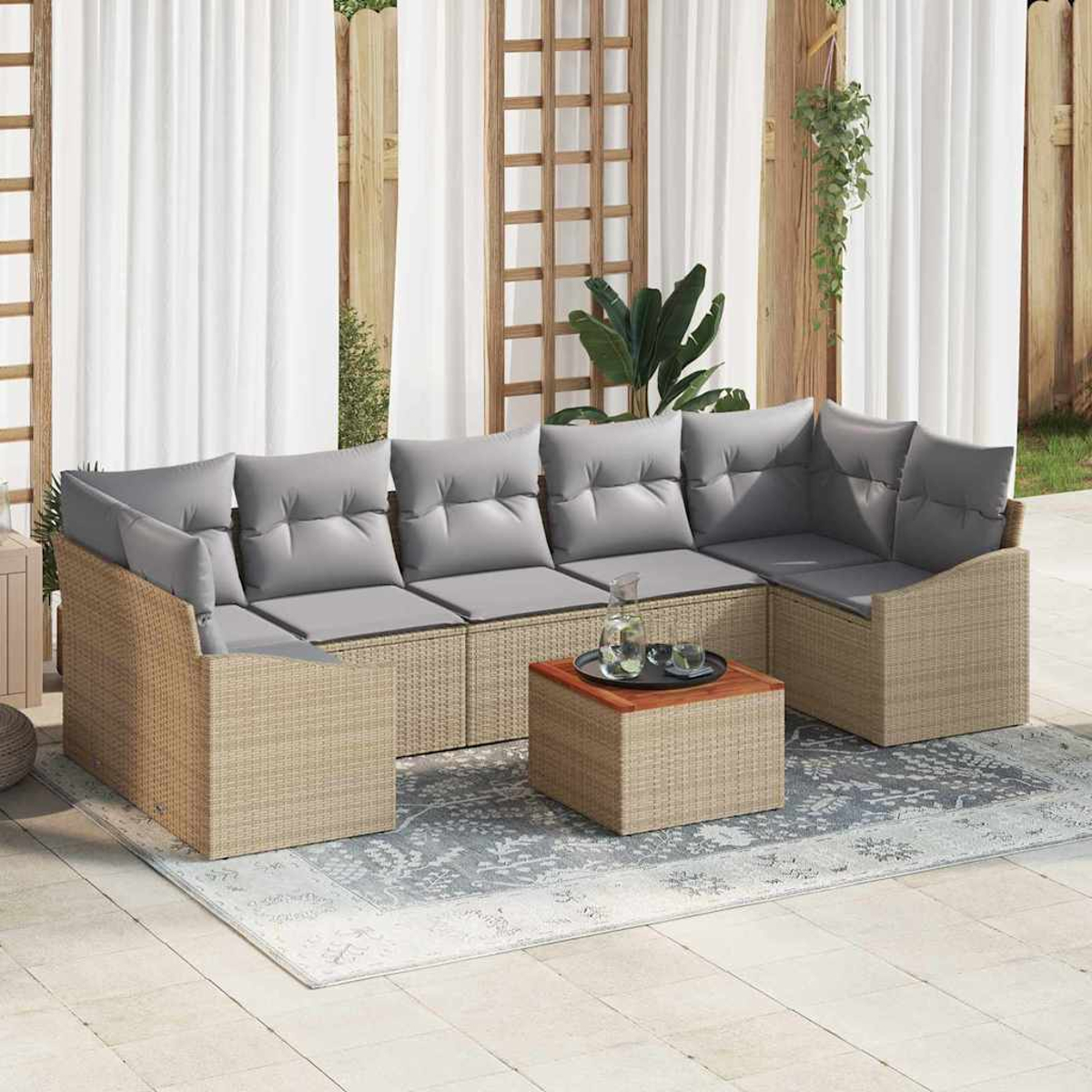 Ein Outdoor-Ecksofa mit grauen Kissen steht auf einem gemusterten Teppich. Ein kleiner Tisch hat Getränke. Weiße Vorhänge und Holzakzente sind im Hintergrund.
