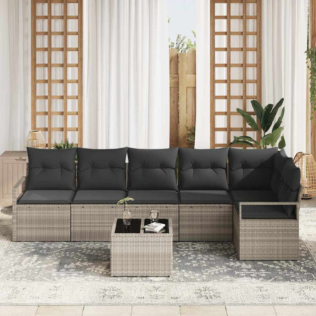 Outdoor-Ecksofa mit grauen Kissen. Davor steht ein quadratischer Couchtisch. Weiße Vorhänge und Holzgitter dahinter.