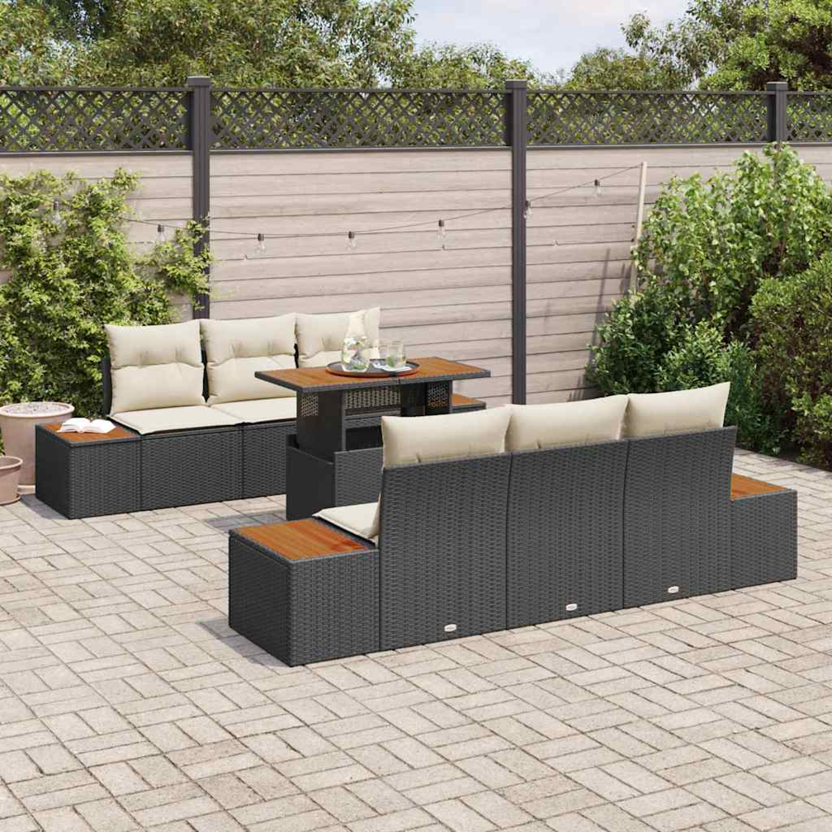 Outdoor-Terrassenset mit dunkelgrauen Möbeln, beigen Kissen und einem Holztisch. Auf Steinpflaster mit Zaunhintergrund.