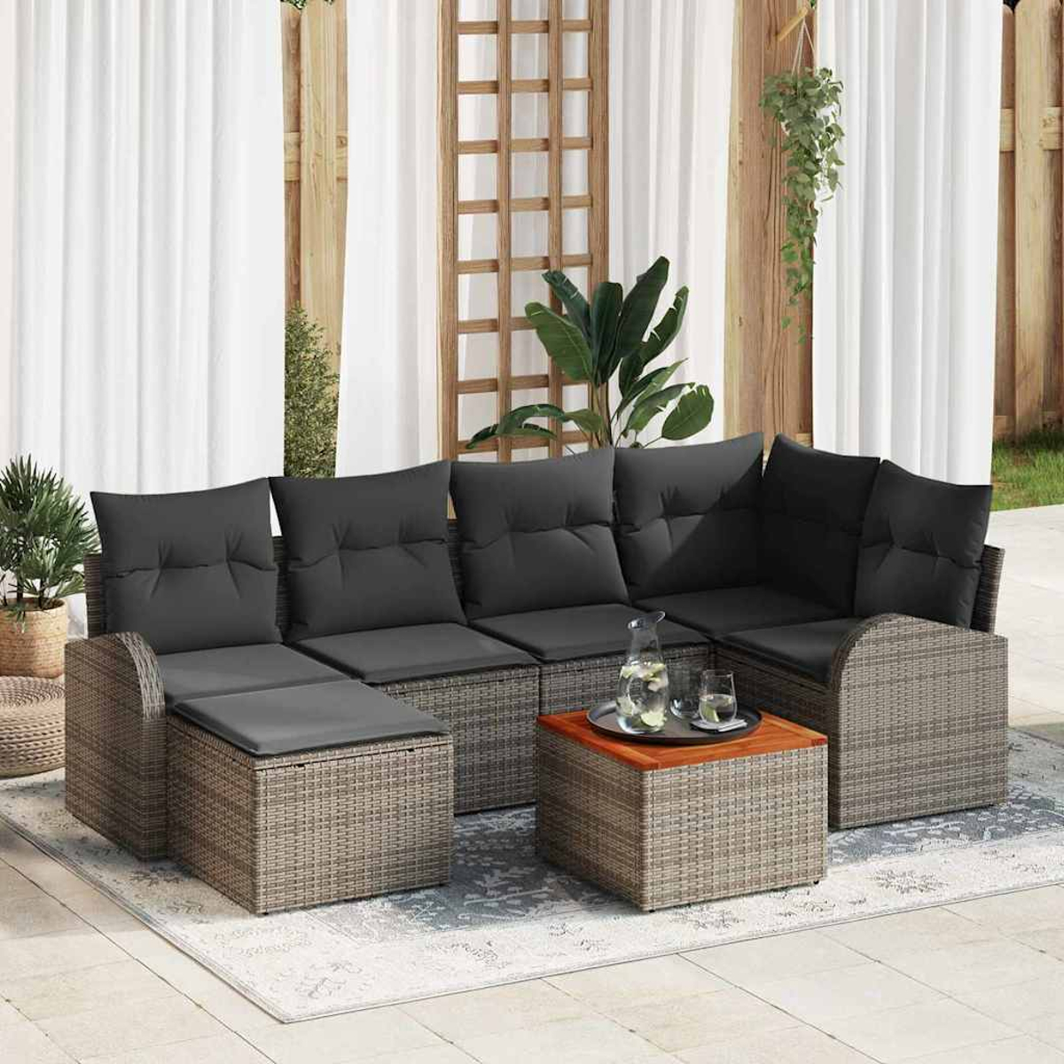 Outdoor-Ecksofa mit grauen Kissen, einem Holztisch mit Getränken und Pflanzen. Weiße Vorhänge und ein Holzgitter im Hintergrund.
