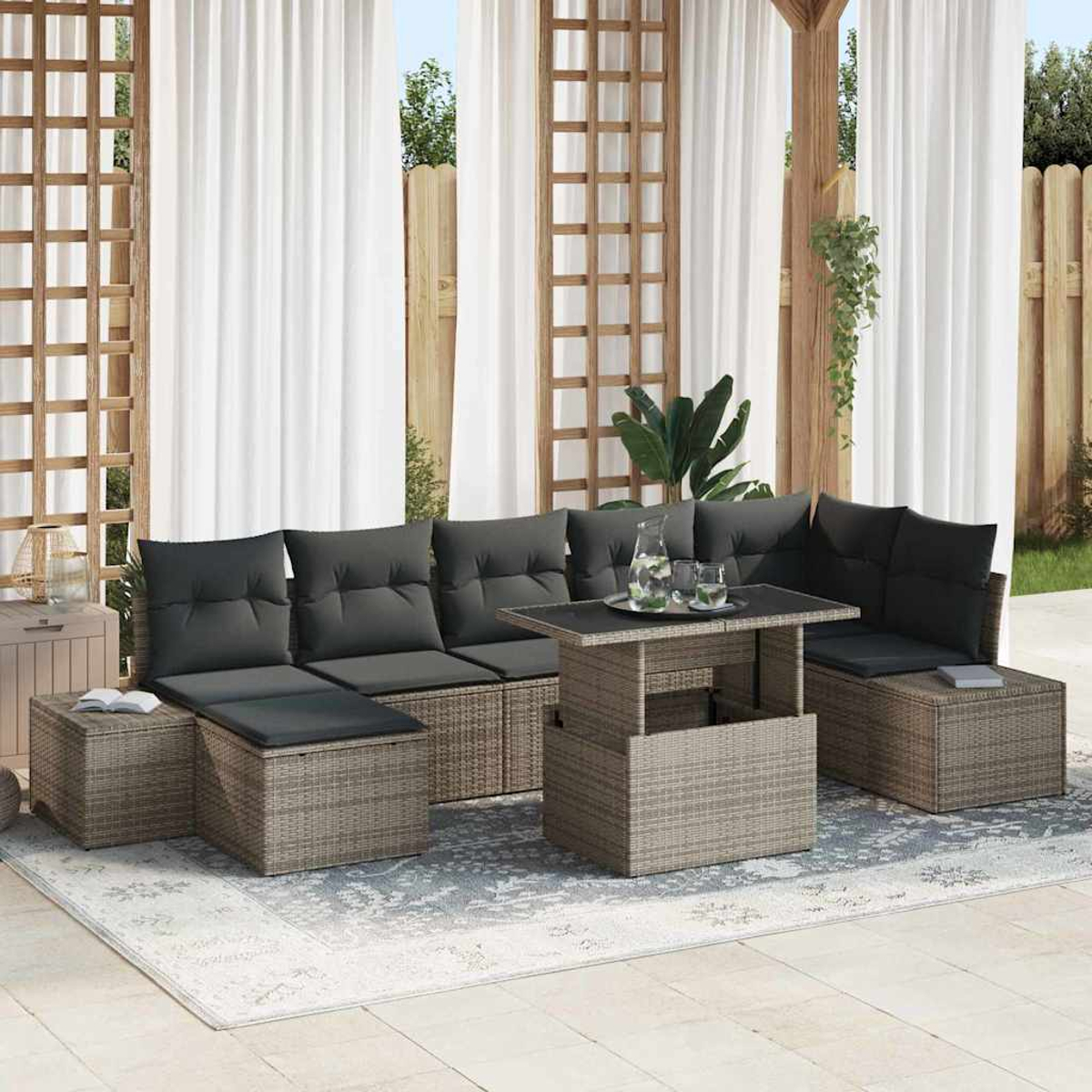 Garten-Terrassenset mit grauen Kissen, einem Tisch mit Gläsern und weißen Vorhängen im Hintergrund. Das Set steht auf einem gemusterten Teppich.