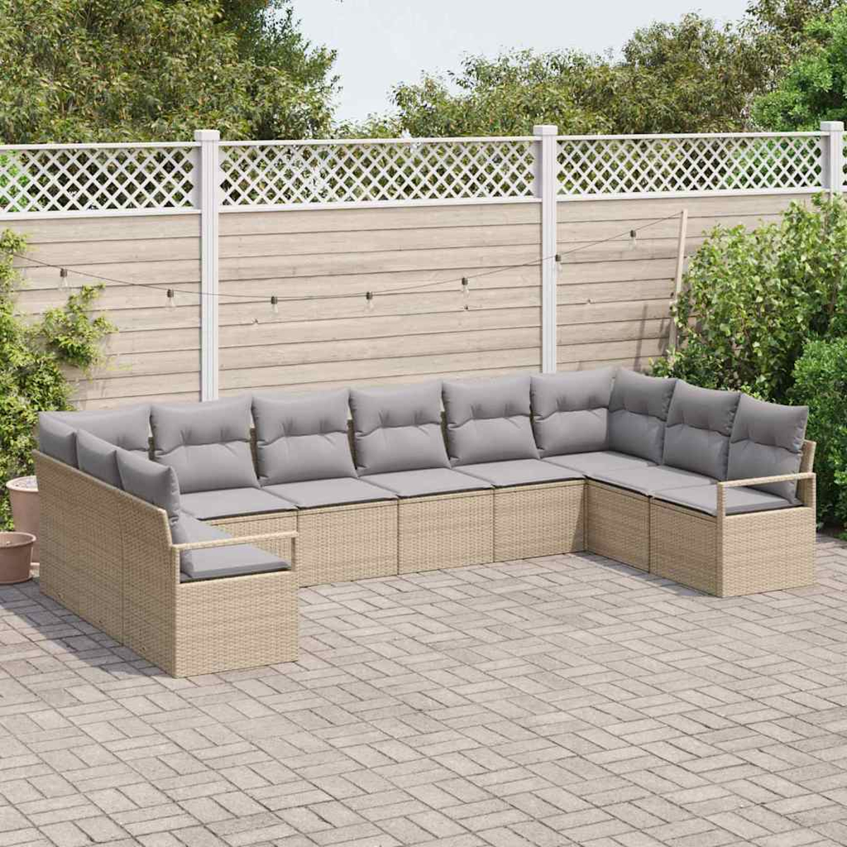 Outdoor-Ecksofa mit grauen Kissen auf einer Backstein-Terrasse. Beiger Korbrahmen. Ein weißer Zaun und grüne Pflanzen im Hintergrund.