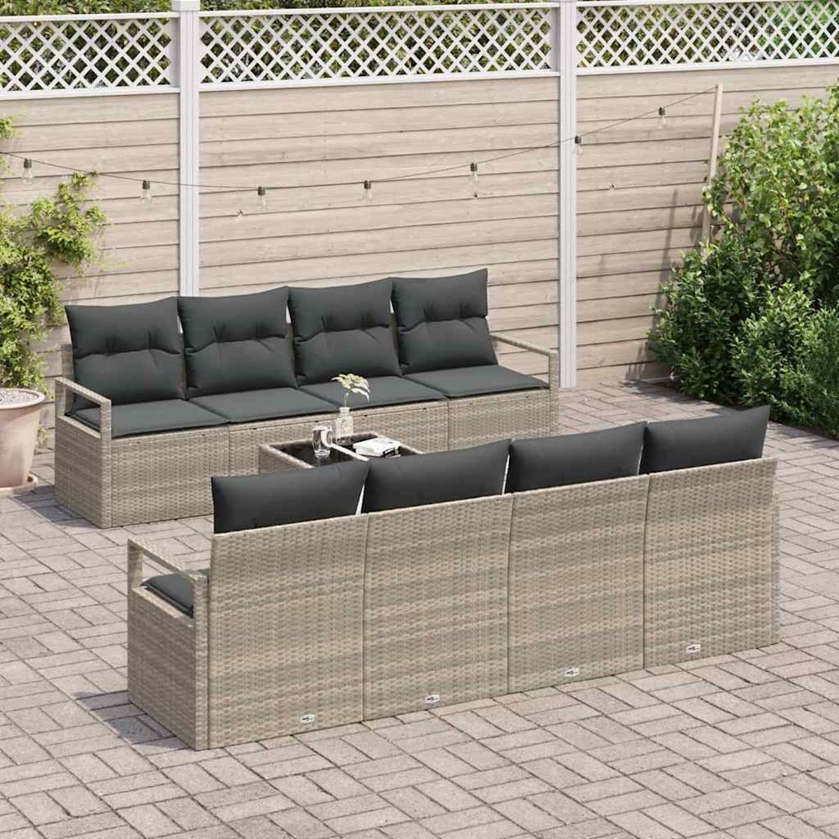 Outdoor-Sitzgruppe mit grauen Kissen, einem Couchtisch und einem Holzzaun. Die Szene deutet auf eine entspannte Umgebung im Freien hin.