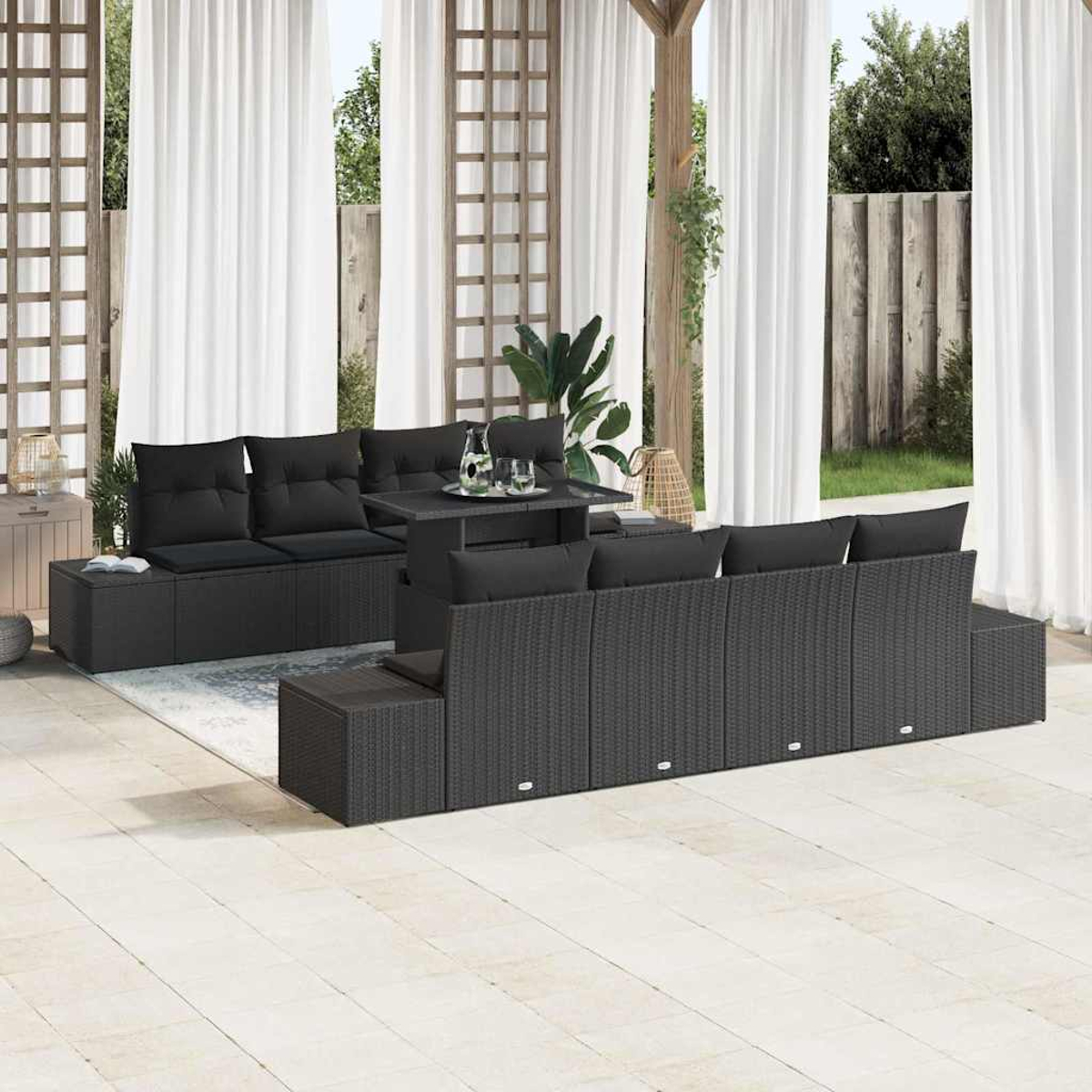 Juego de patio al aire libre con cojines negros sobre muebles de mimbre grises. Incluye una mesa y cortinas en el fondo.