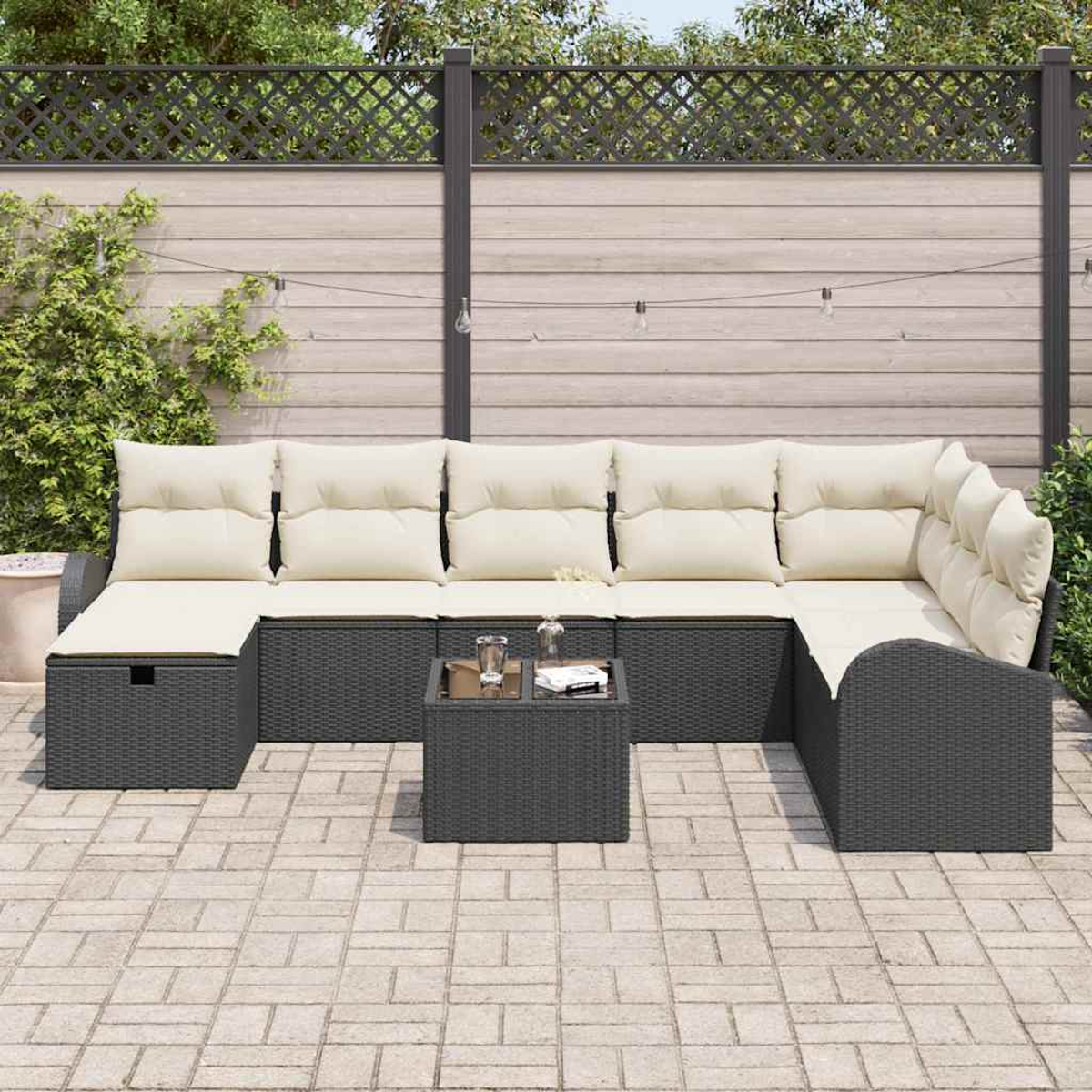 Ein Ecksofa im Freien mit cremefarbenen Kissen und einem kleinen quadratischen Tisch. Der Hintergrund zeigt einen Holzzaun und Grün.