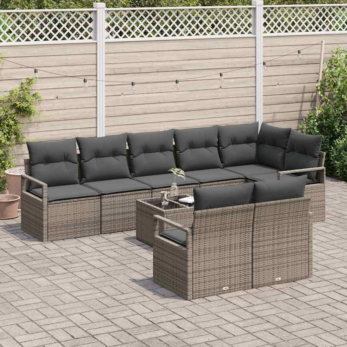 Garten-Set mit grauen Kissen auf einem KorbgGestell. Enthält ein Ecksofa, zwei Stühle und einen kleinen Glastisch.