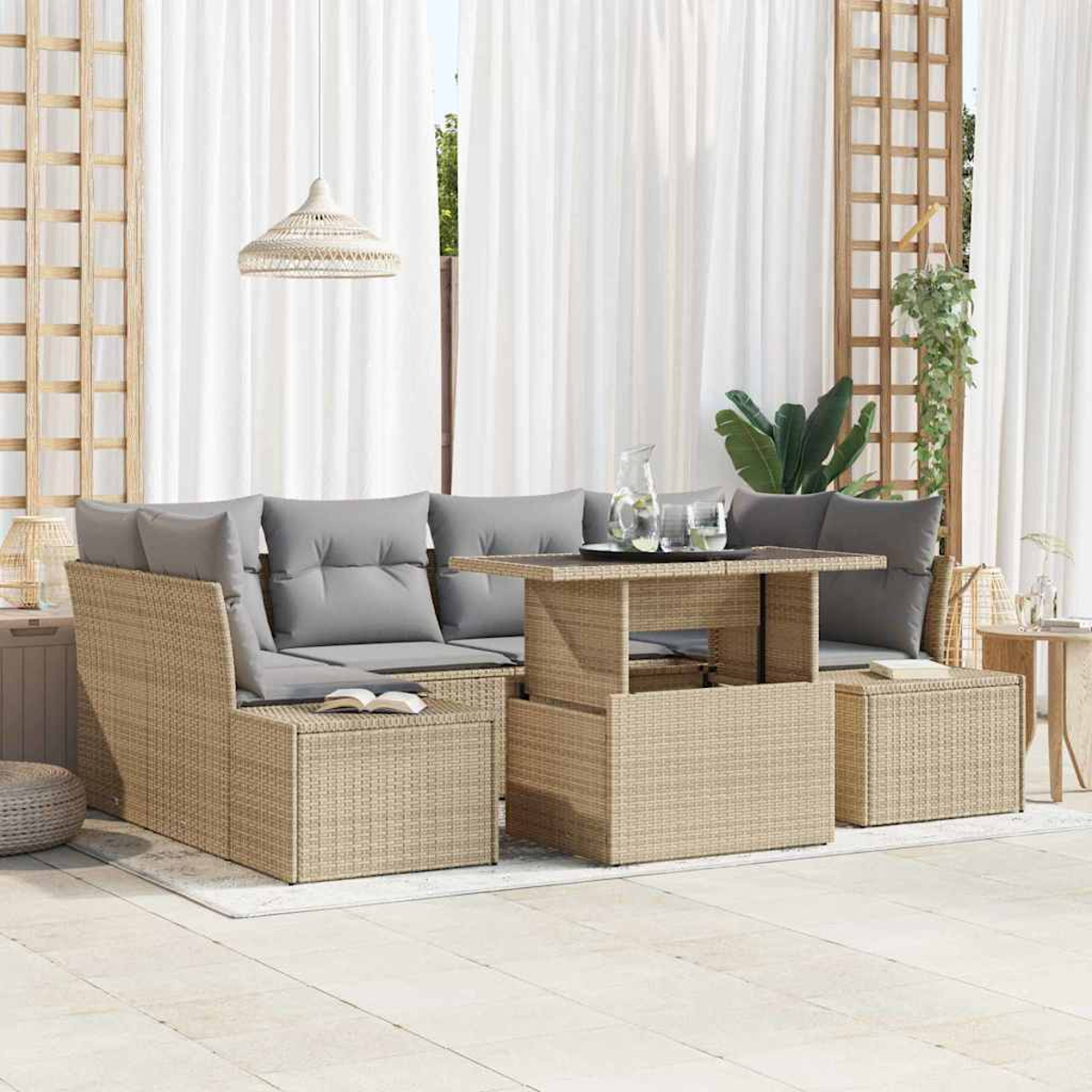 Gartenmöbel-Set aus Korbgeflecht mit grauen Kissen, einem Tisch und einer Hängelampe. Weiße Vorhänge und eine grüne Pflanze im Hintergrund.