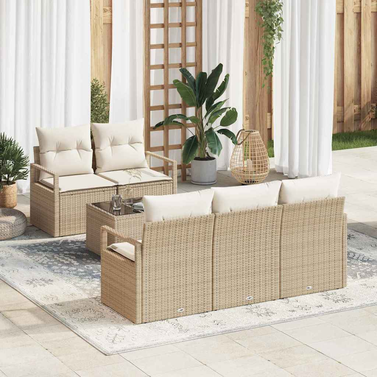 Terrassenmöbel-Set mit beigen Korbmöbeln, weißen Kissen, Teppich und Pflanzen. Szene umfasst Sofa, Stühle und einen kleinen Tisch.