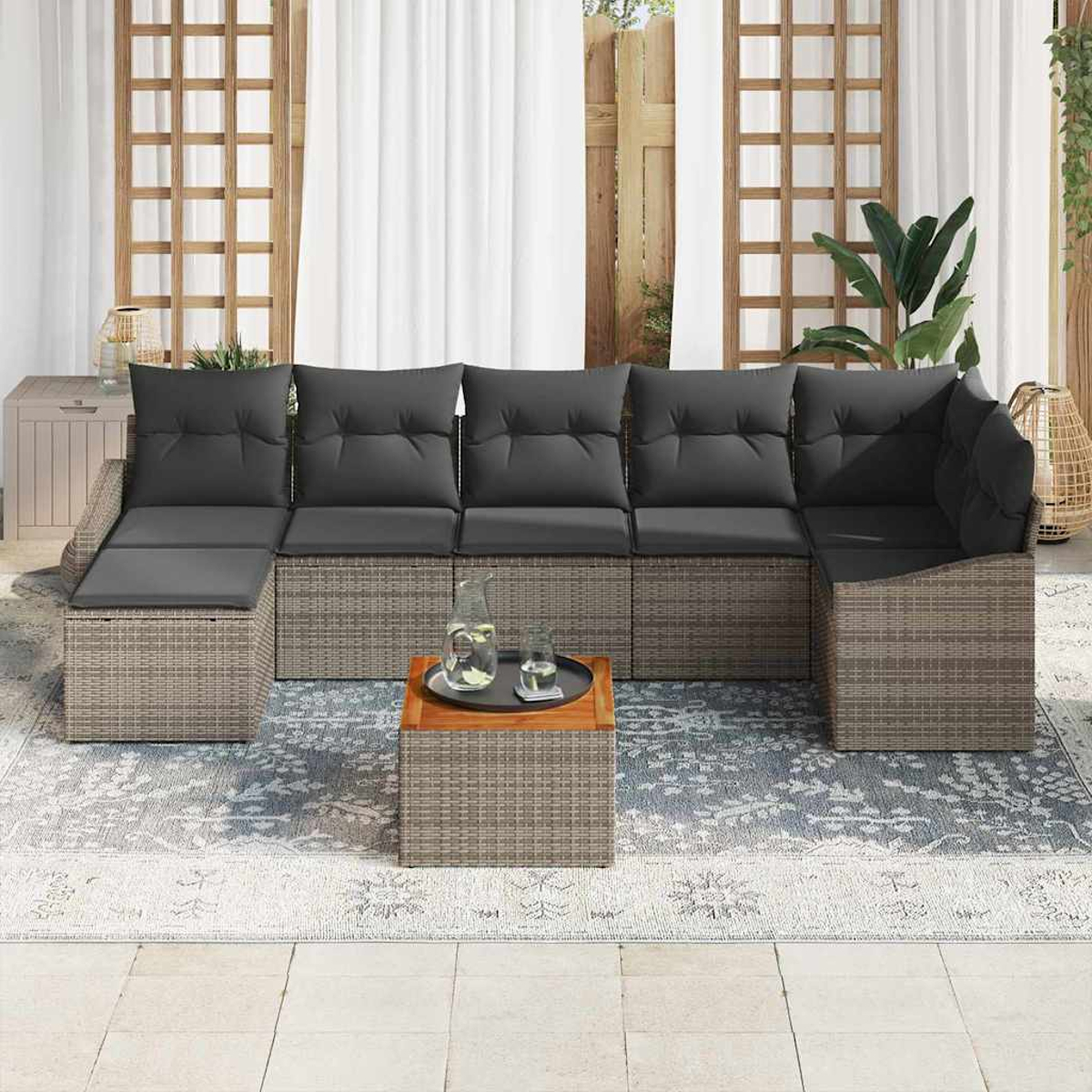 Outdoor-Ecksofa mit grauen Kissen. Ein kleiner Holztisch mit Getränken steht auf einem gemusterten Teppich. Weiße Vorhänge im Hintergrund.