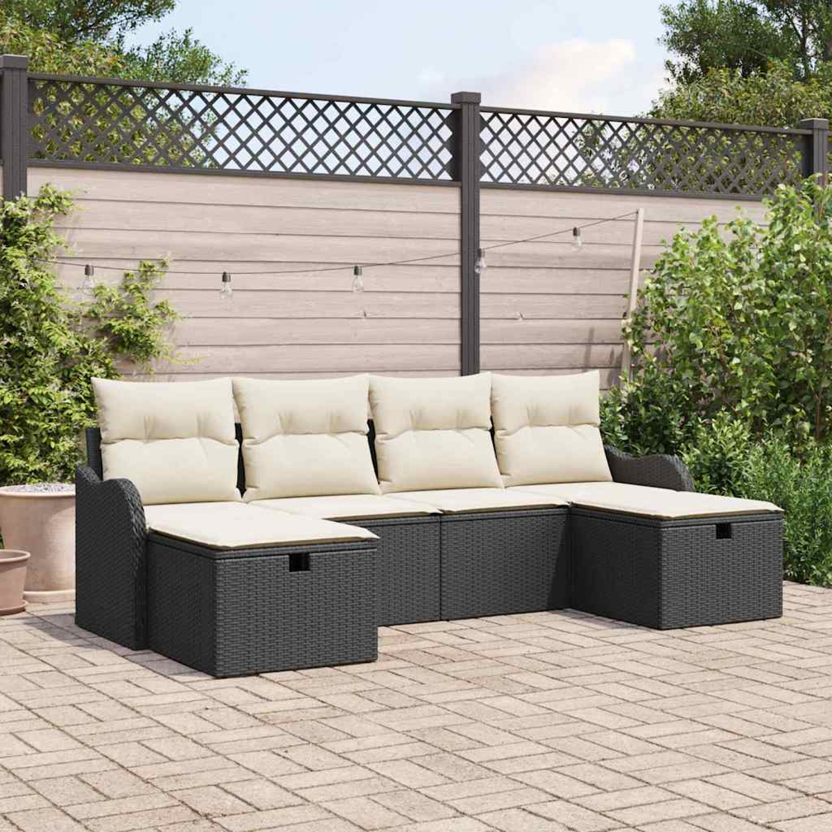 Outdoor-Ecksofa mit cremefarbenen Kissen. Es steht auf einer Backstein-Terrasse, im Hintergrund ein Zaun und Grün.